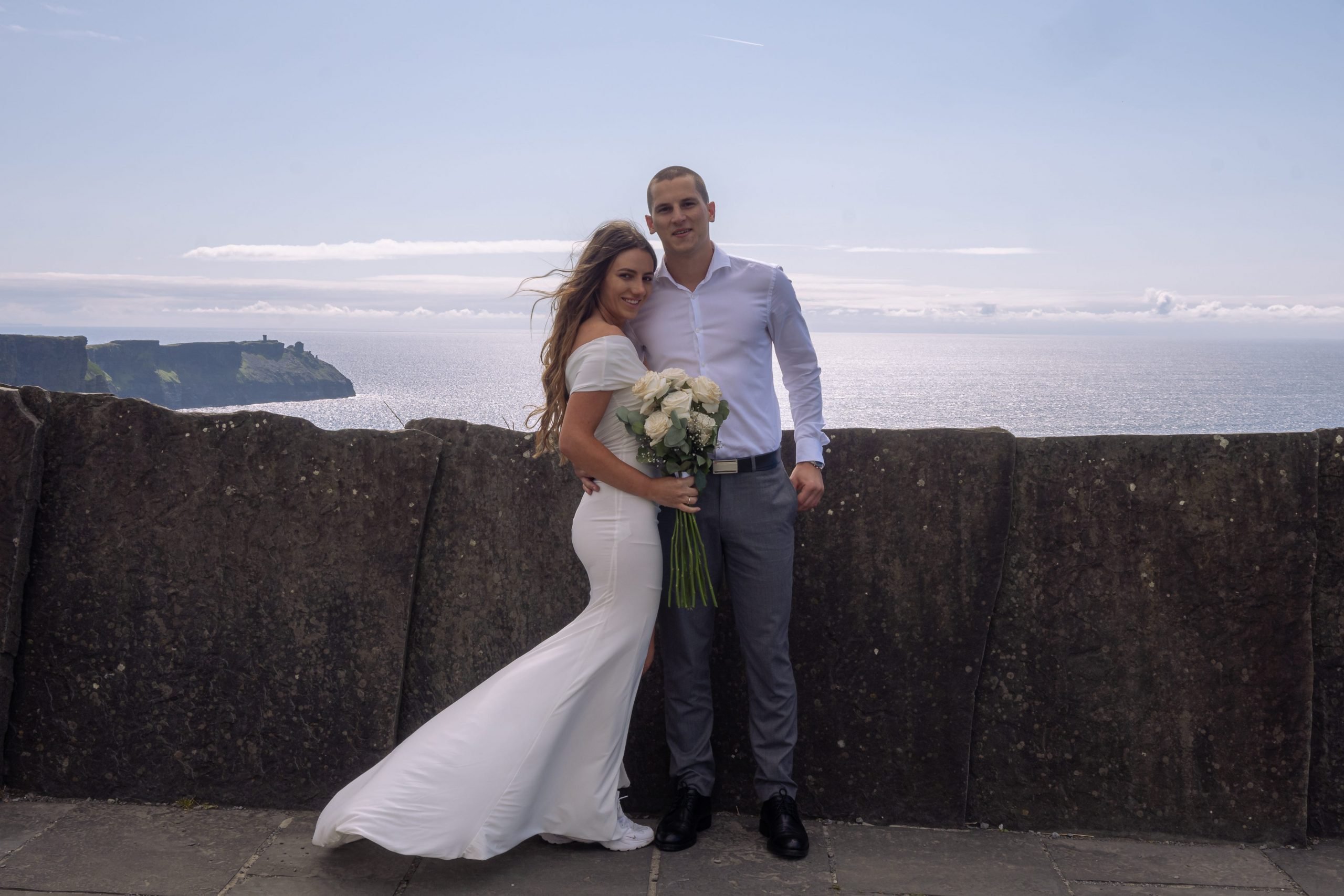 The couple, photographed by Kevin Hennessy, wearing wedding attire in front of the Cliffs of Moher, Ireland.