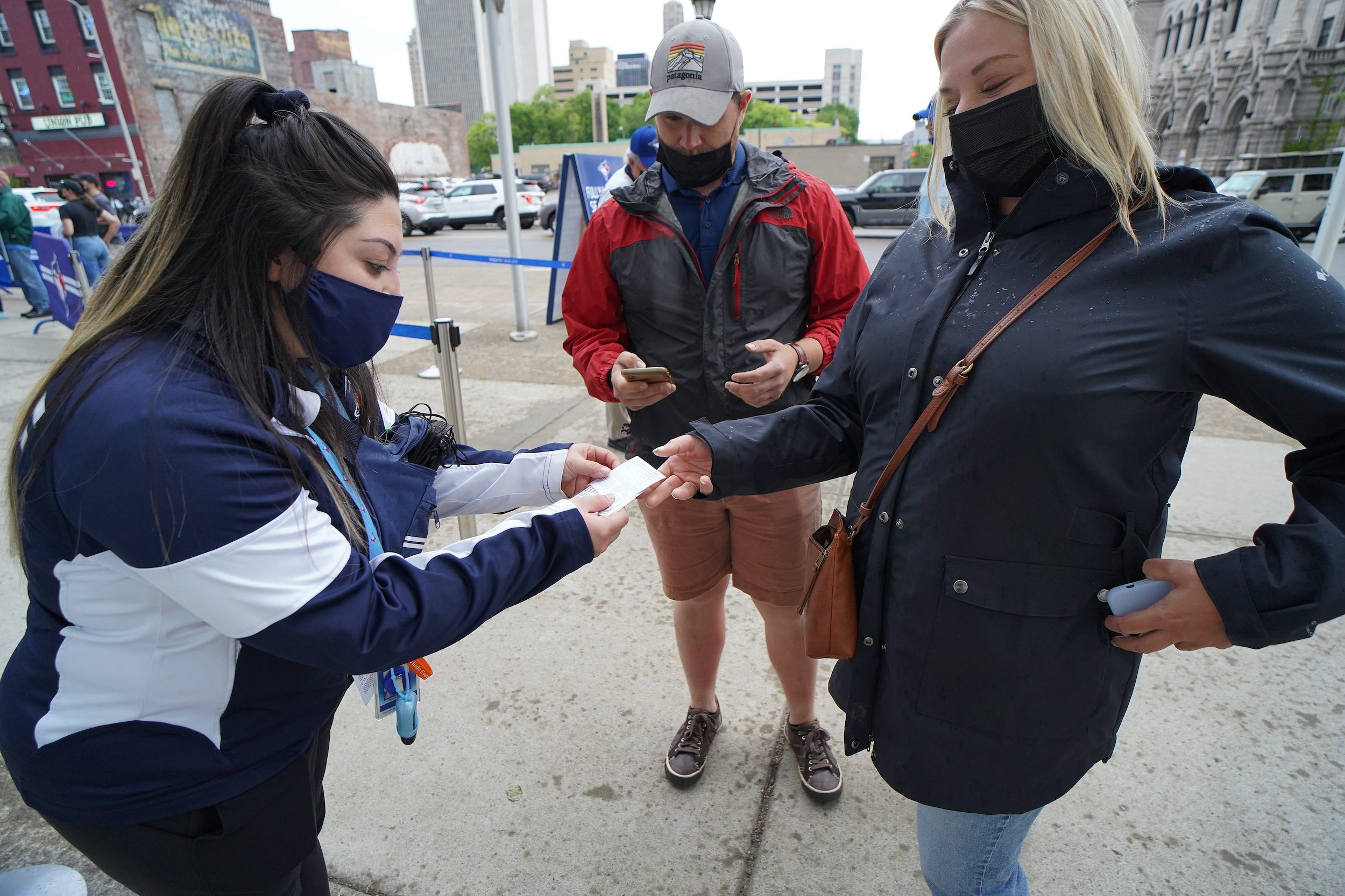 Woman checks vaccine card of attendee at baseball game