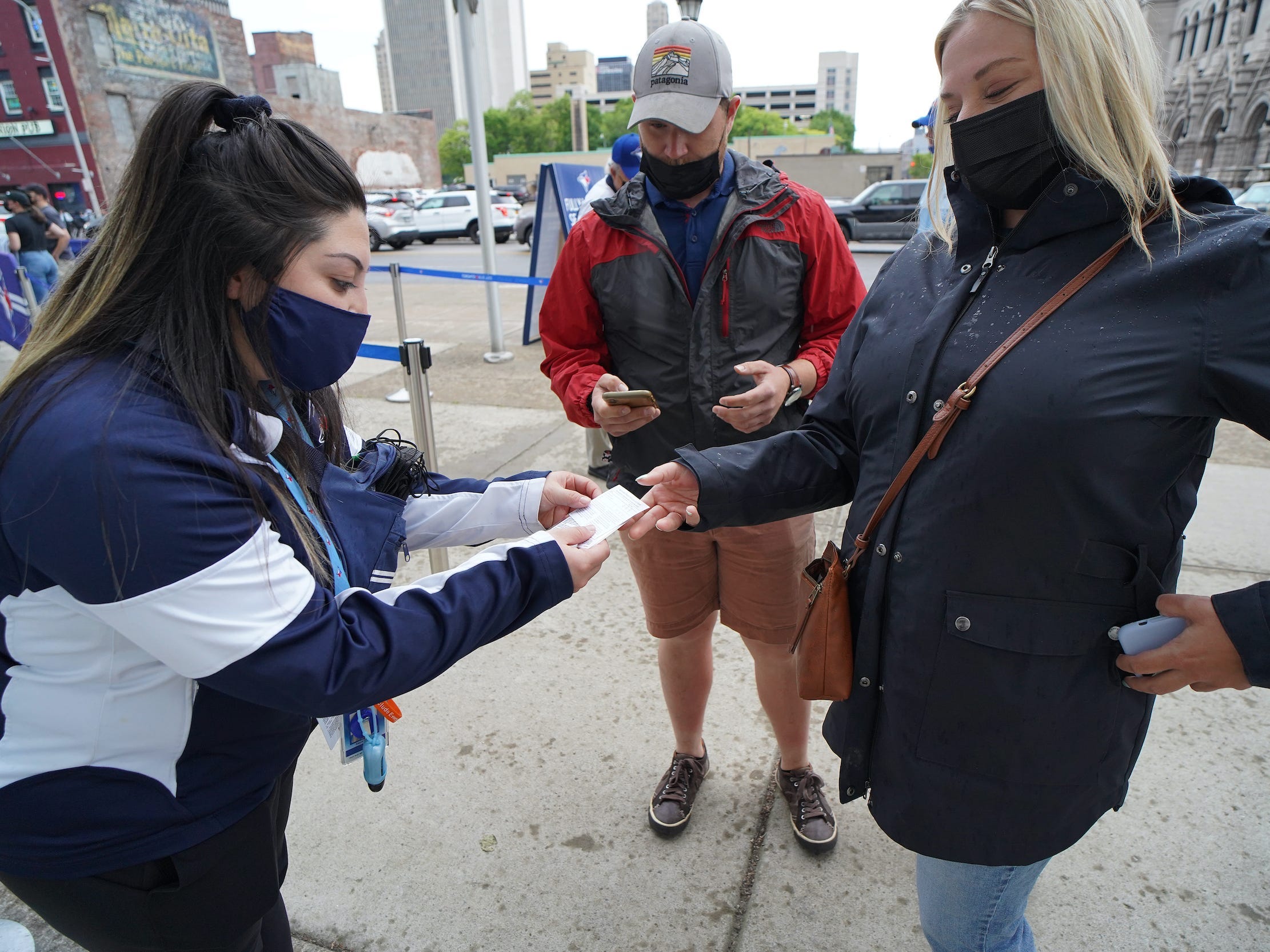 Woman checks vaccine card of attendee at baseball game