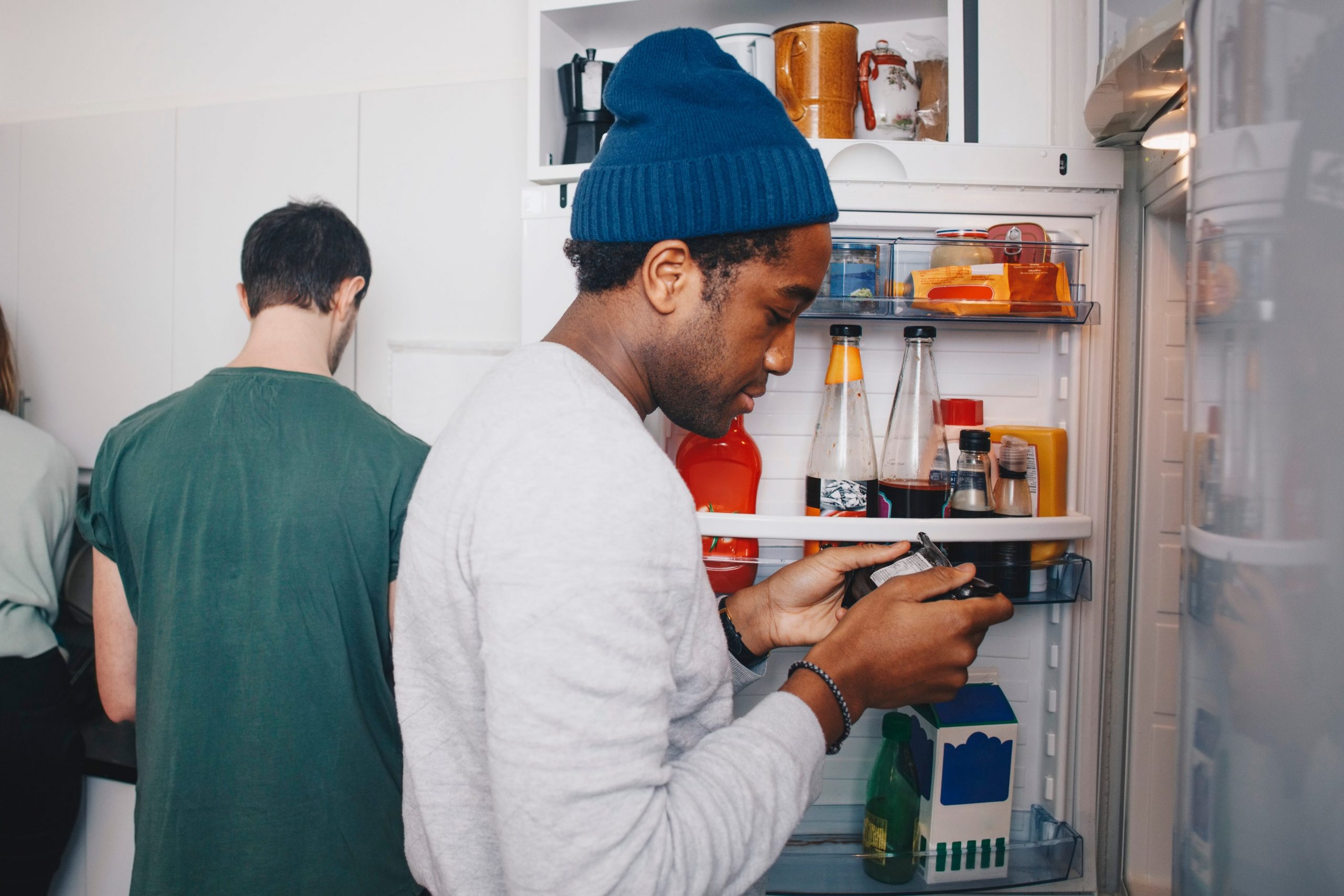 man reading food label in front of fridge