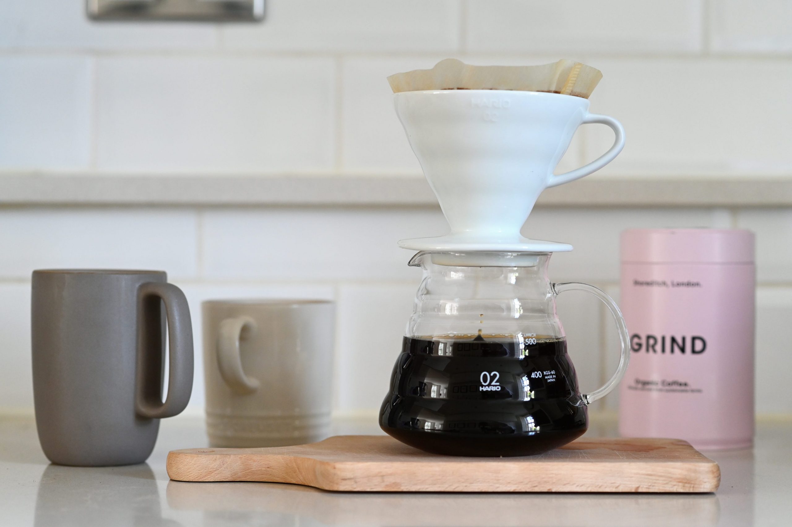 A drop of coffee falls into a half-full coffee pot from a dripper