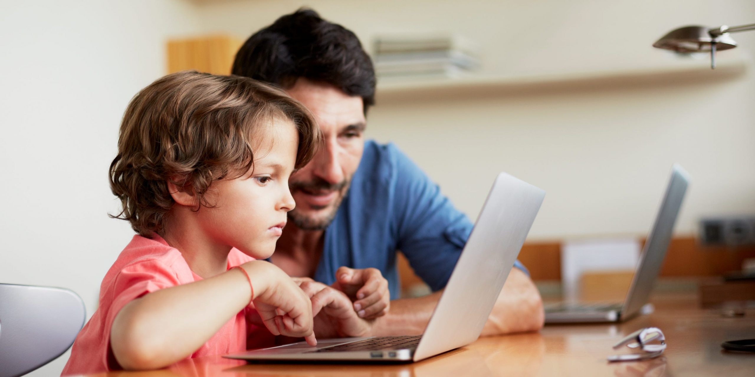 A father and son look at a MacBook Air together.