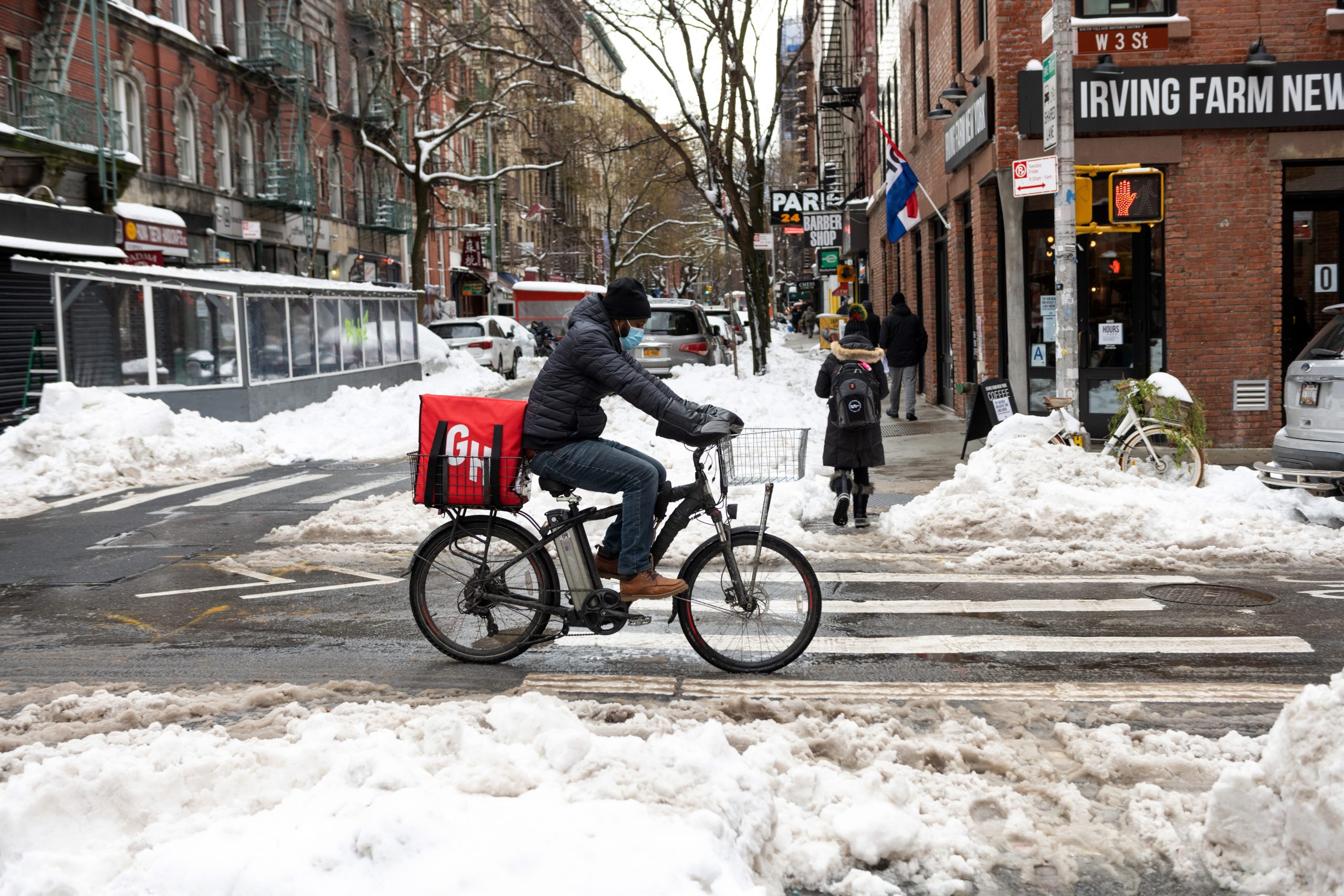 A Grubhub delivery driver rides along partially cleared streets near piles of snow in Greenwich Village on February 03, 2021 in New York City. New York City and much of the Northeast was hit by a major winter storm