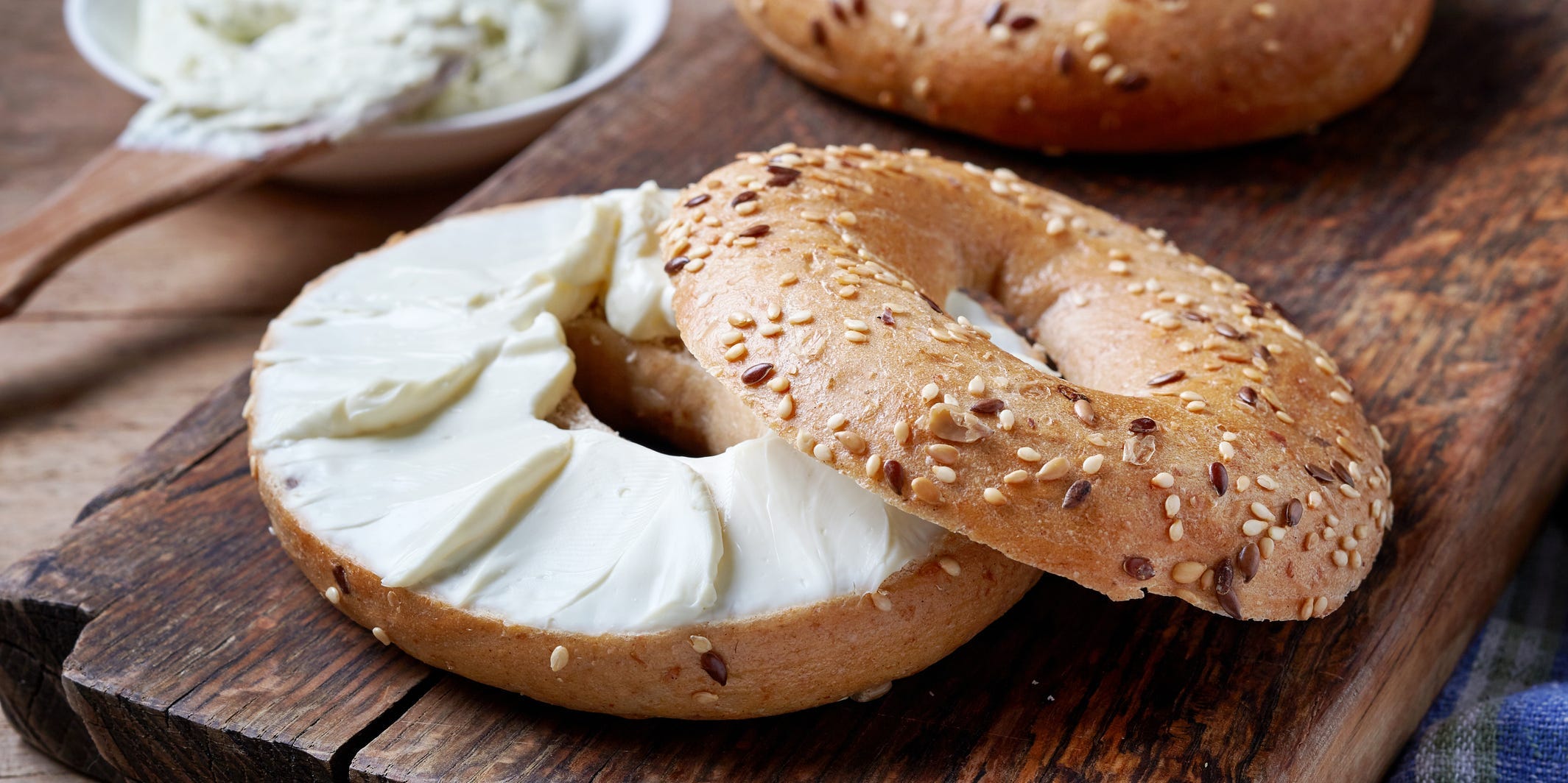 A sesame bagel cut in half and topped with cream cheese