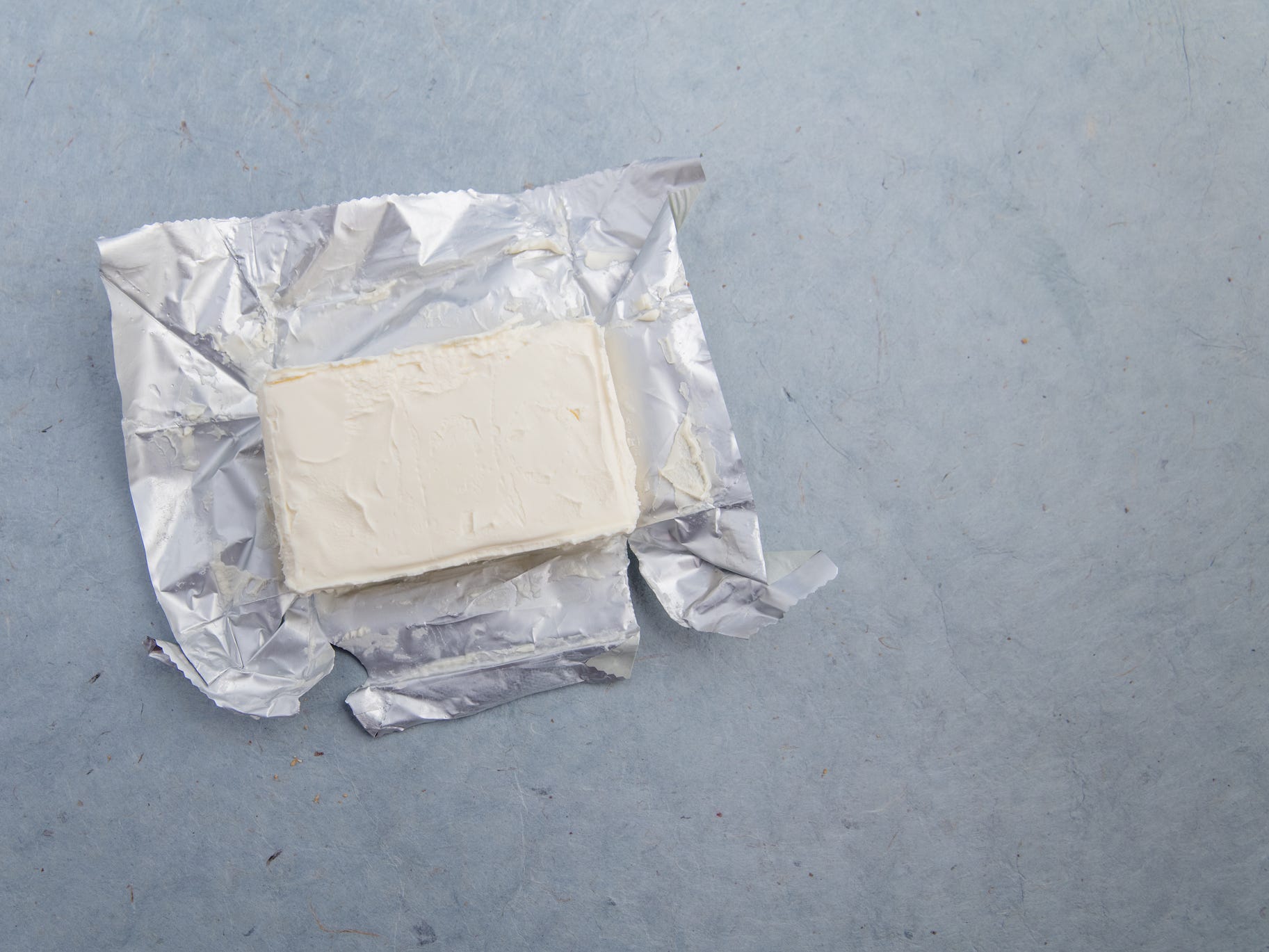 A block of cream cheese sitting on top of its foil packaging