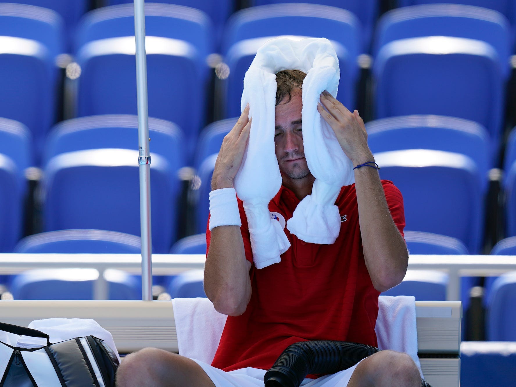Daniiel Medvedev holds a towel to his head at the Tokyo Olympics.