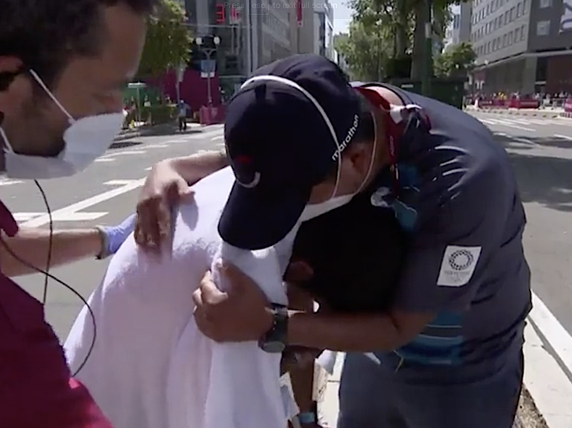 Claudio Villanueva Flores cries in the arms of a coach after the 50km race walk at the Tokyo Olympics