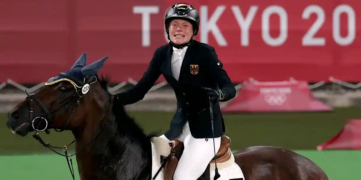 Modern pentathlete Annika Schleu pictured crying on her horse after the horse refused to jump.