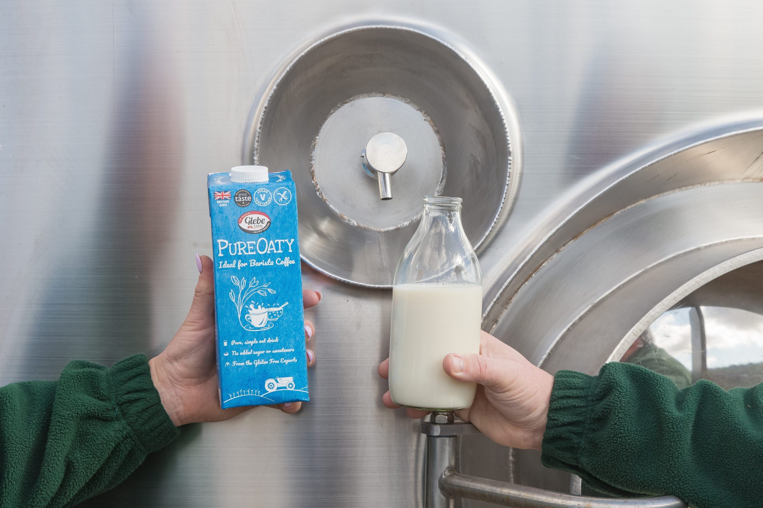 A jar of PureOaty held next to a carton of the same milk substitute