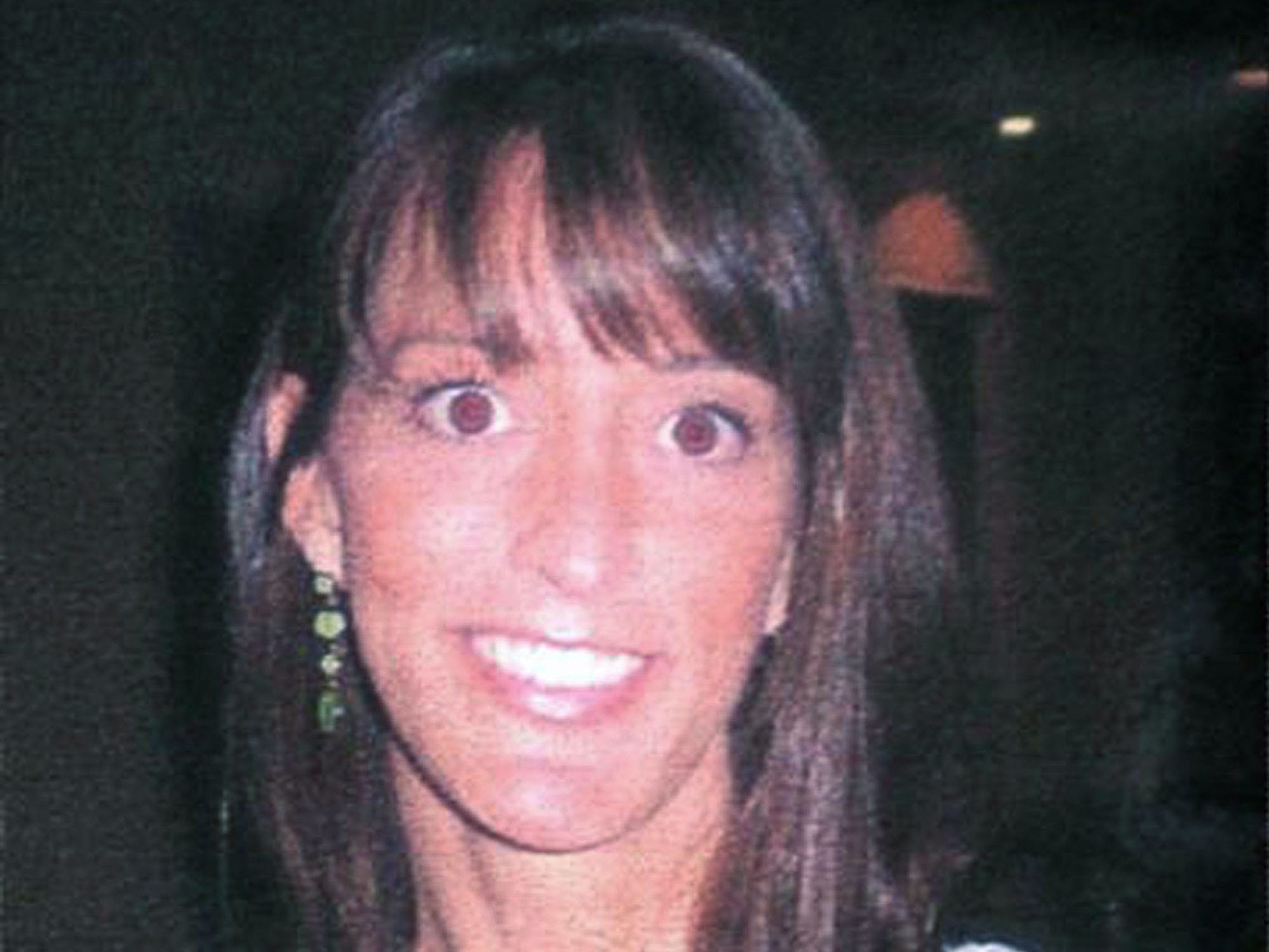 A woman with brown hair and brown eyes smiles for a picture.