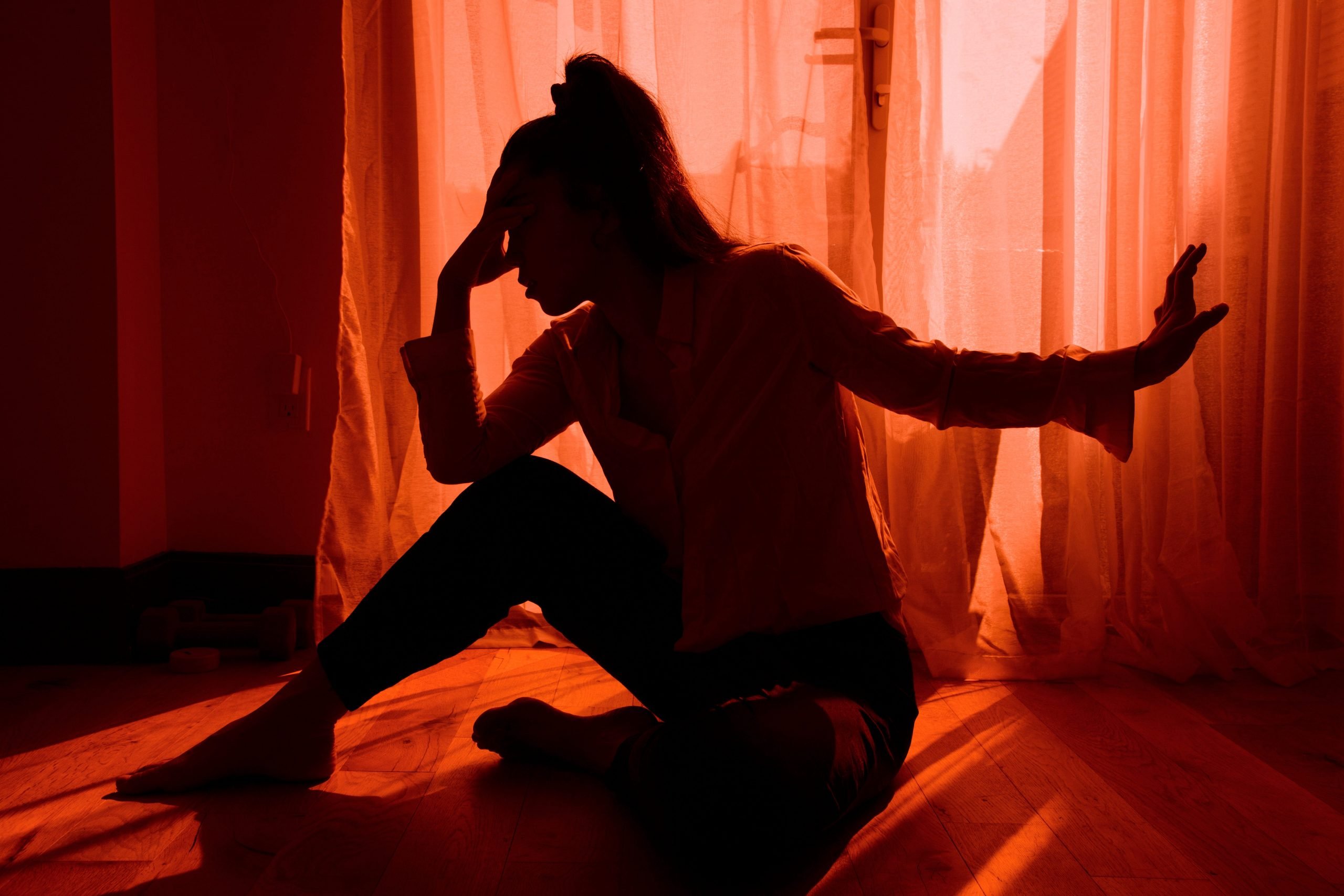 Woman looking stressed and upset against a window.