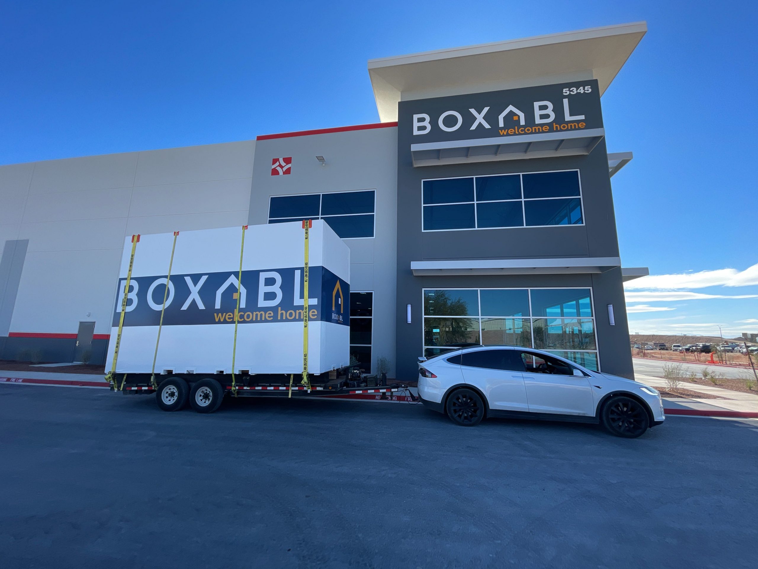 boxabl logo on moving containers being pulled by Tesla