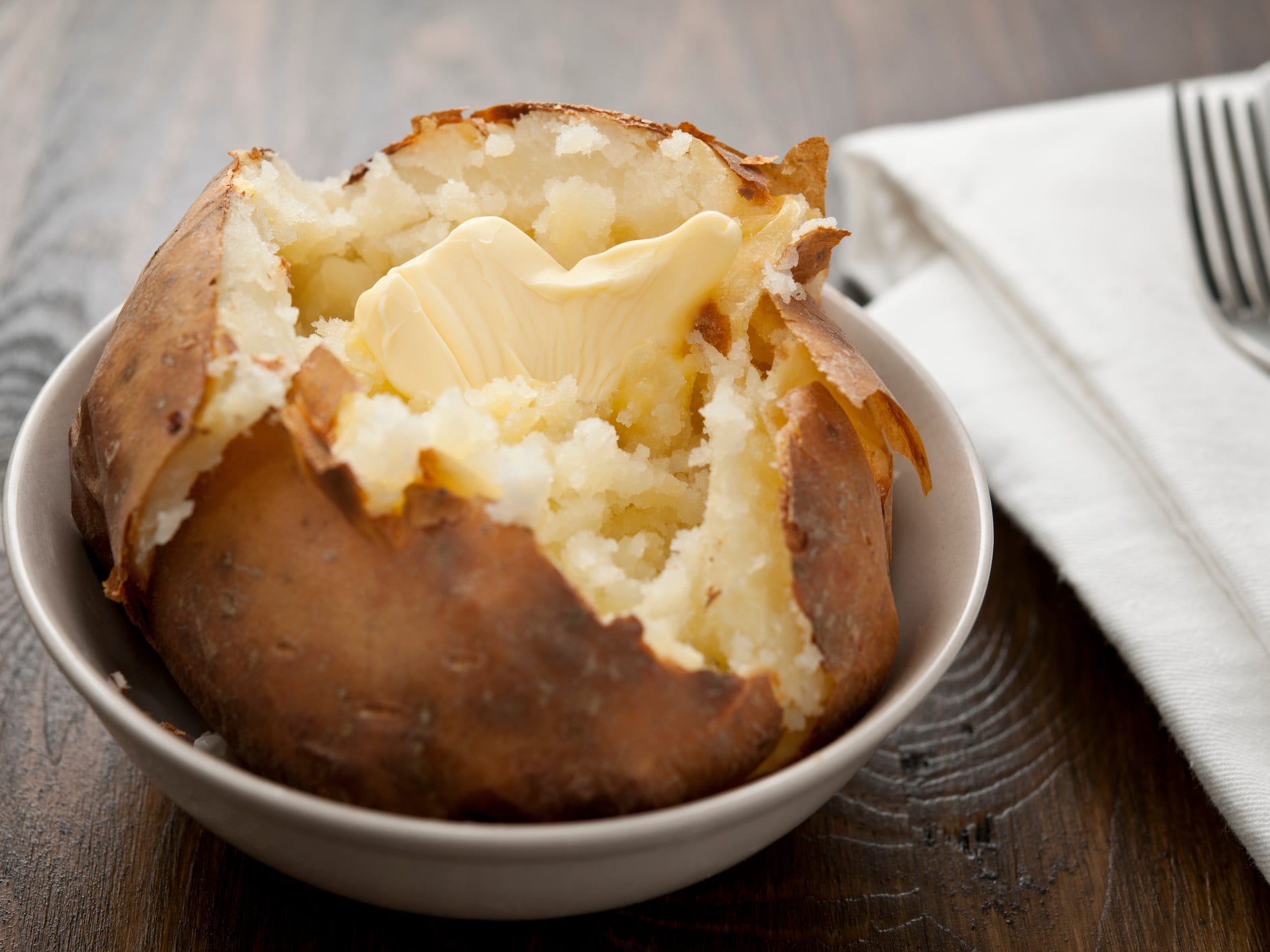 Baked potato in a bowl with butter on top.