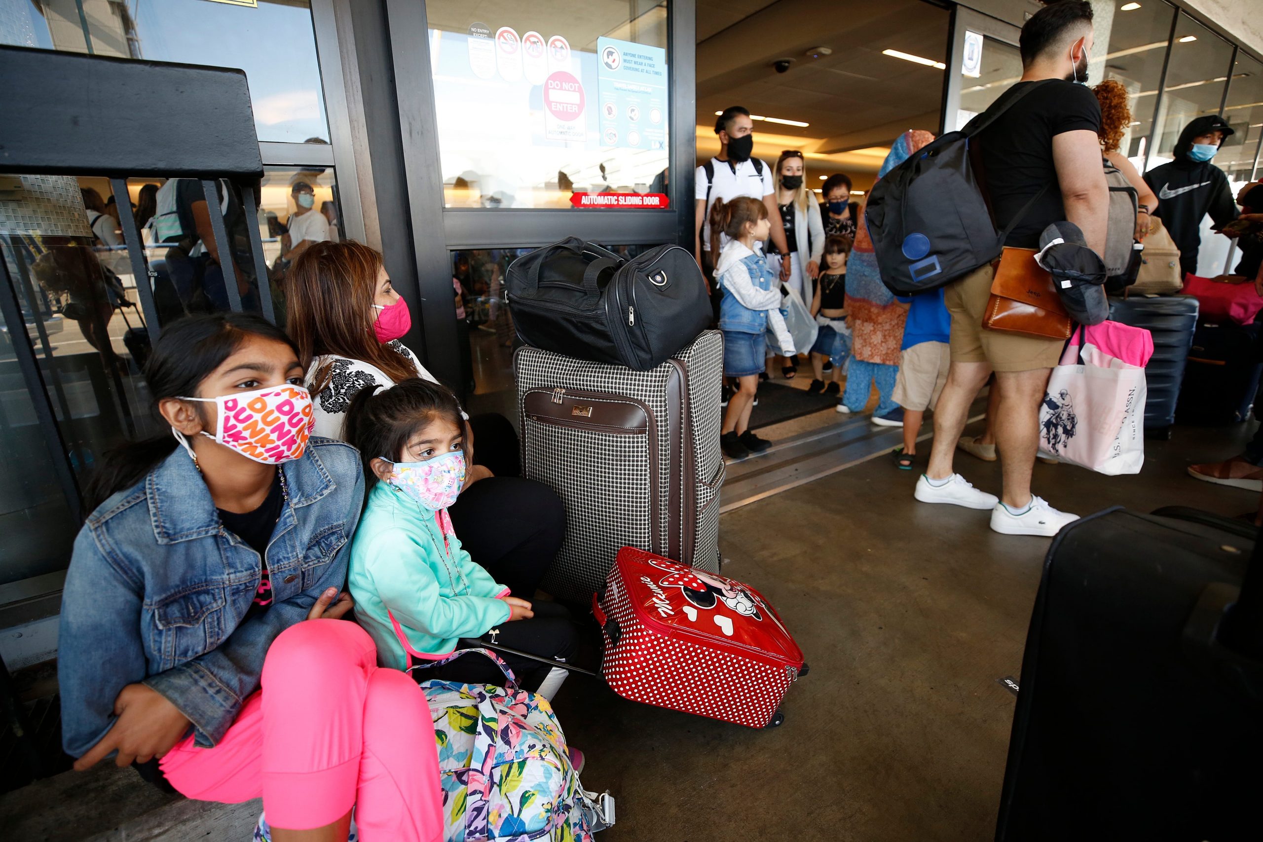 Nizma Jumani, 11, and sister Alizay 4, Jumani, traveling back home to Chicago with their Grandmother Noorjahan Bhojani, wait with other passengers as they form a line that extends outside LAX Terminal 5 Tuesday morning.