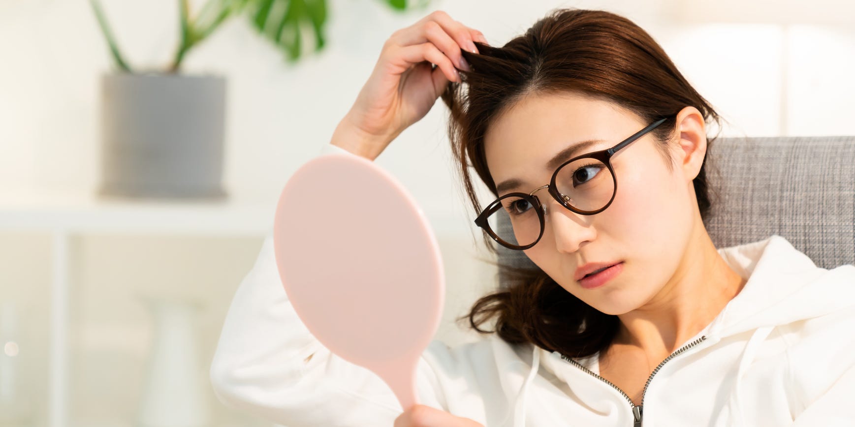 woman looking at hair in mirror