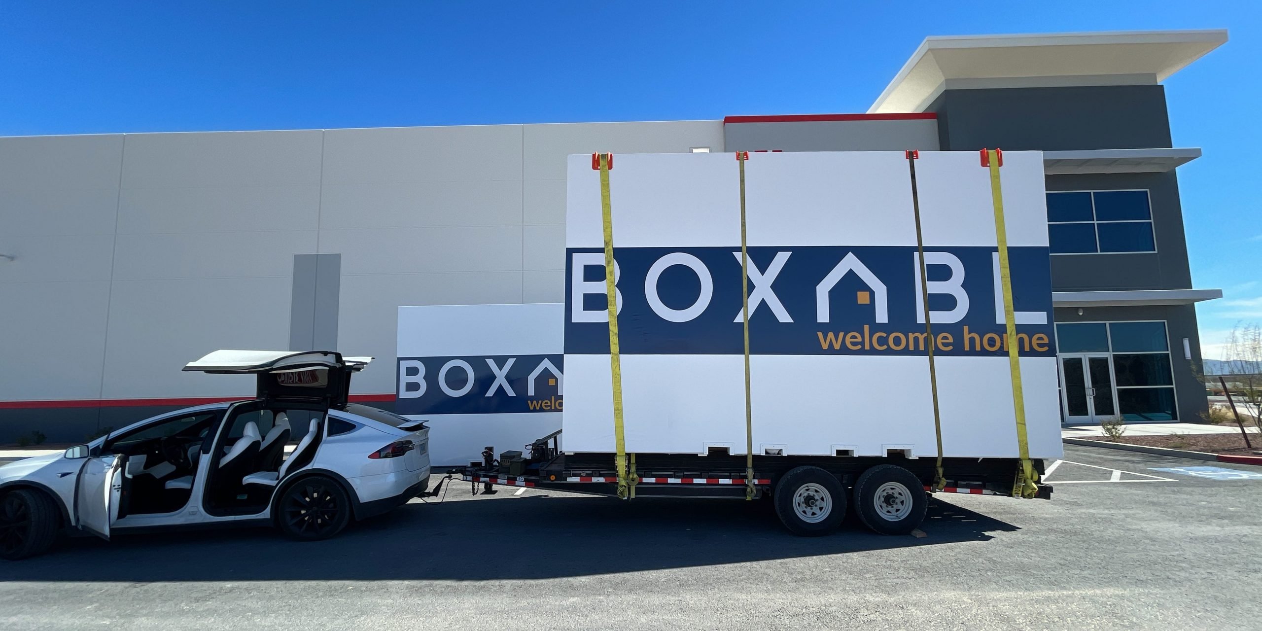 boxabl logo on moving containers being pulled by Tesla