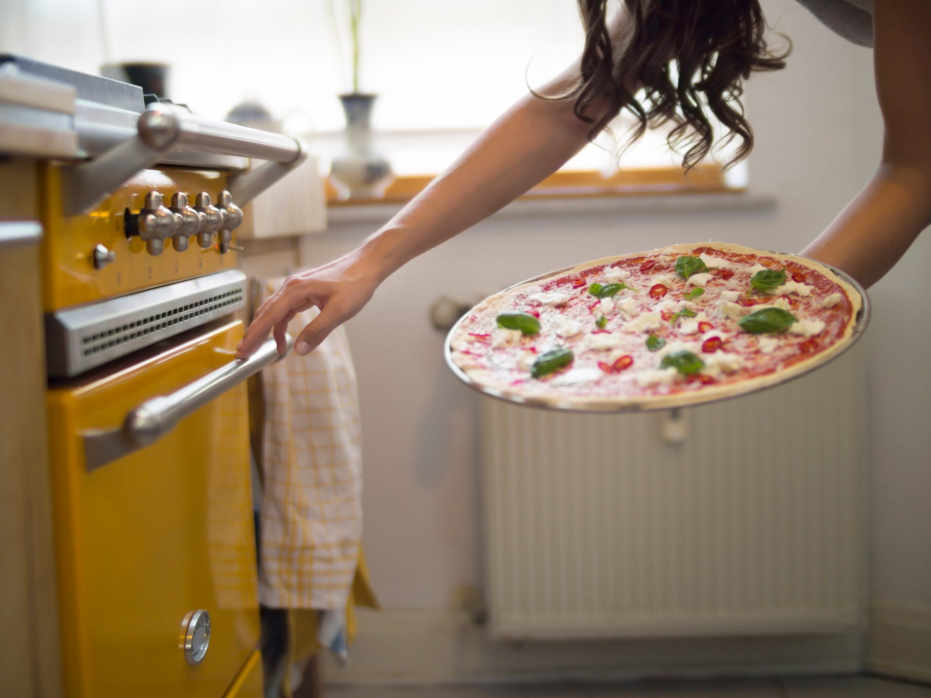 Someone putting a pizza in the oven.