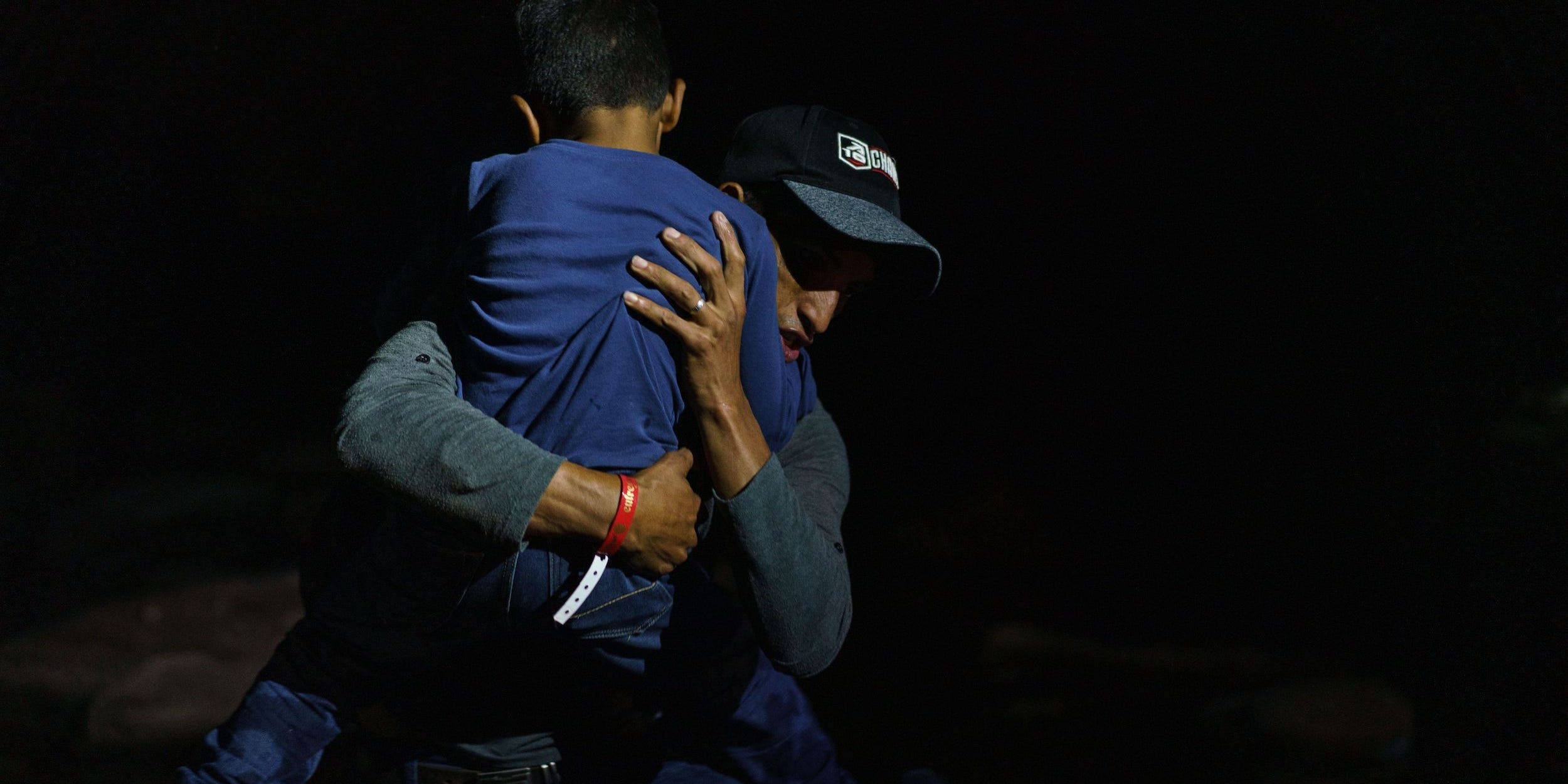 Honduran Eric Villanueva, 31, carries his son Eric, 7, onto the shore of the Rio Grande after crossing the US-Mexico border on a raft into the United States in Roma, Texas on July 9, 2021.