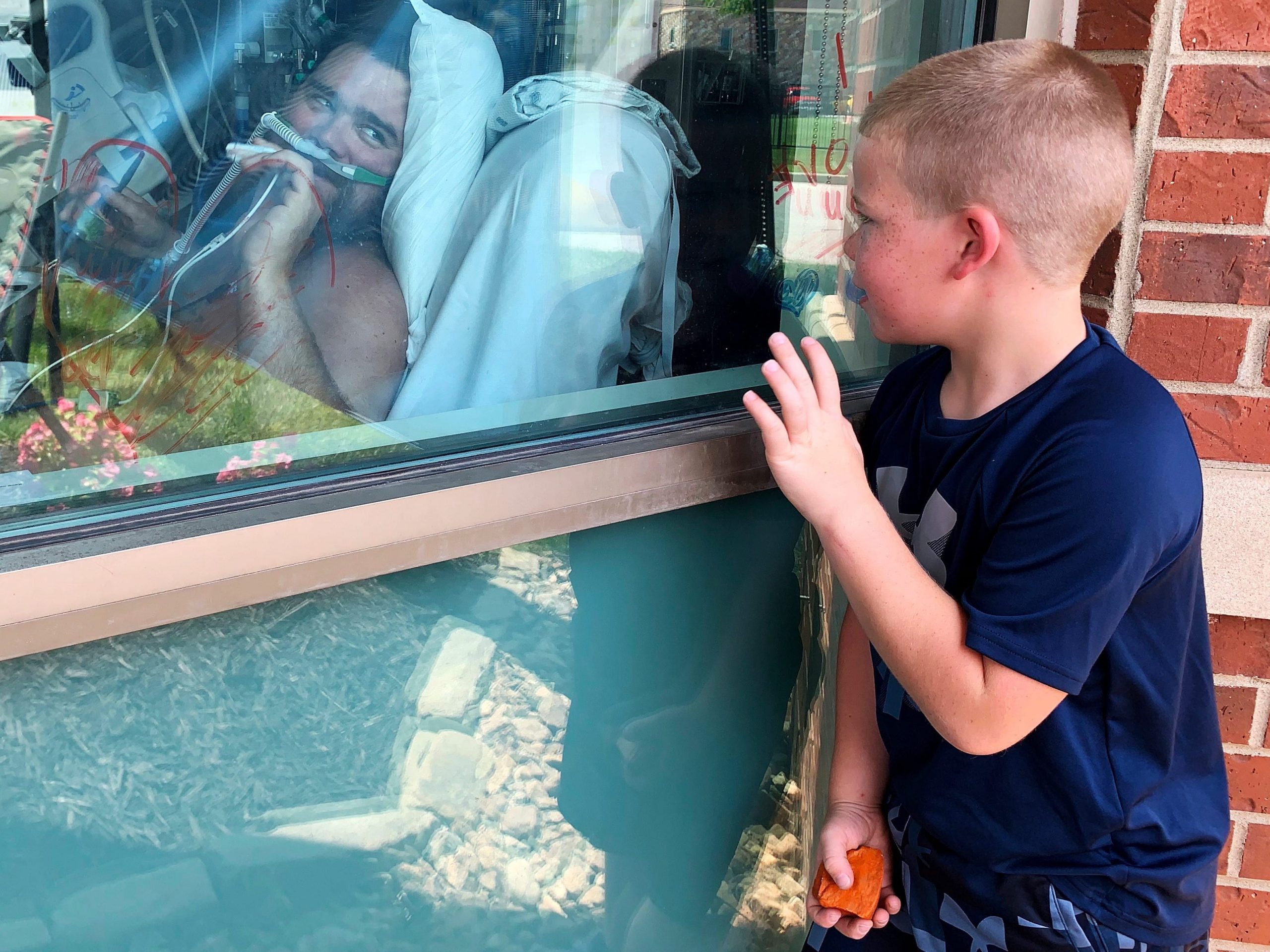 Six-year-old Brody Barker waves to his father, Daryl, from outside his hospital room on Monday, July 26, 2021, in Osage Beach, Mo.