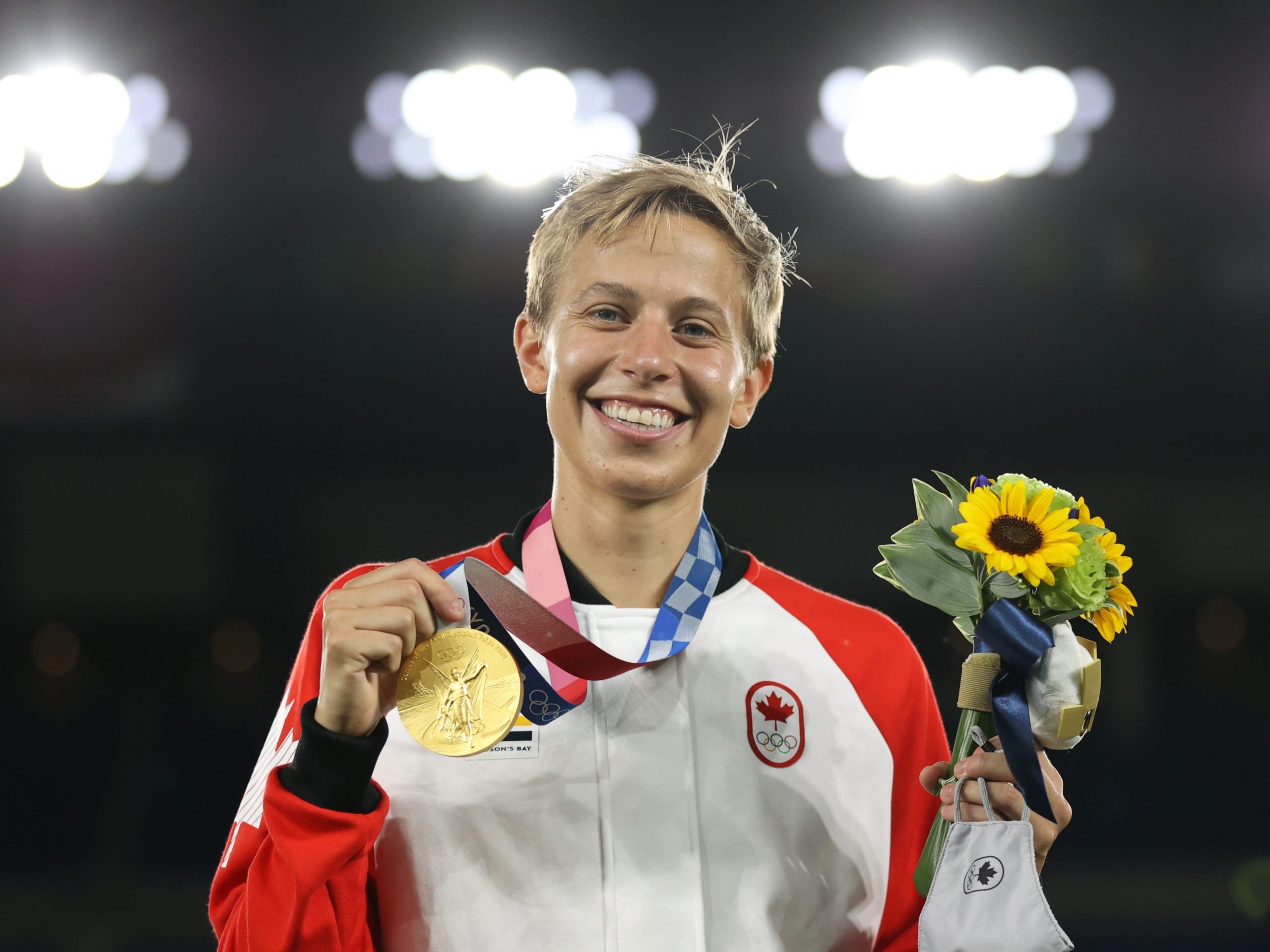 Canada's Quinn holding their Gold medal after Canada's Soccer team win Gold at the Olympics