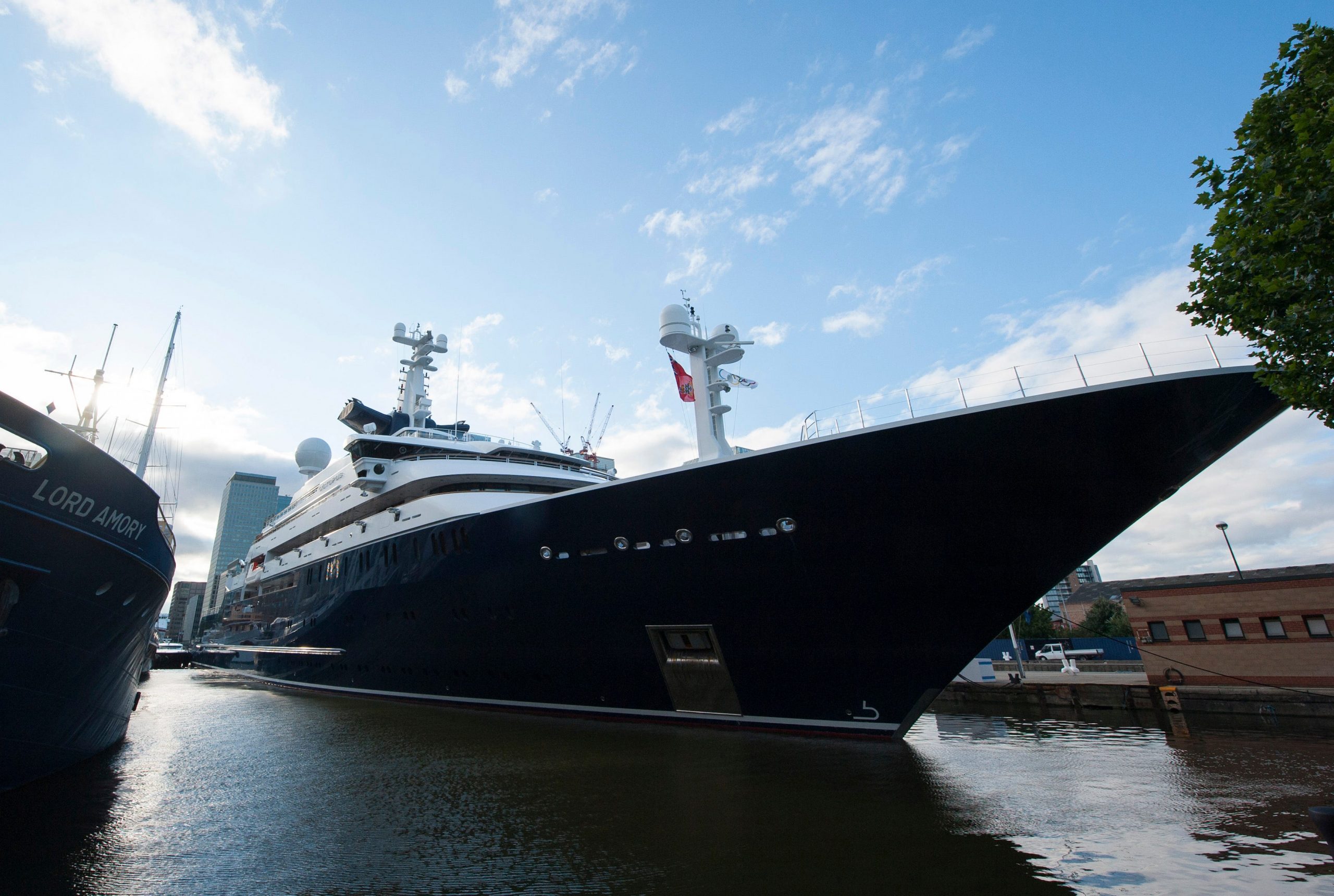 The blue hull of the luxury yacht "Octopus" sits at the dock in London's Canary Wharf