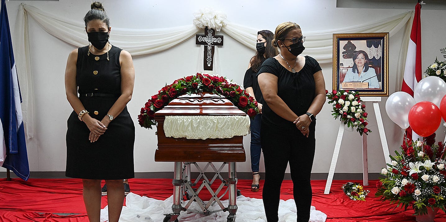 People stand next to the coffin with the remains of former congresswoman from the opposition Liberty Party, Carolina Echeverria Haylock, during her wake at the headquarters of her party, in Tegucigalpa, on 26 July 2021