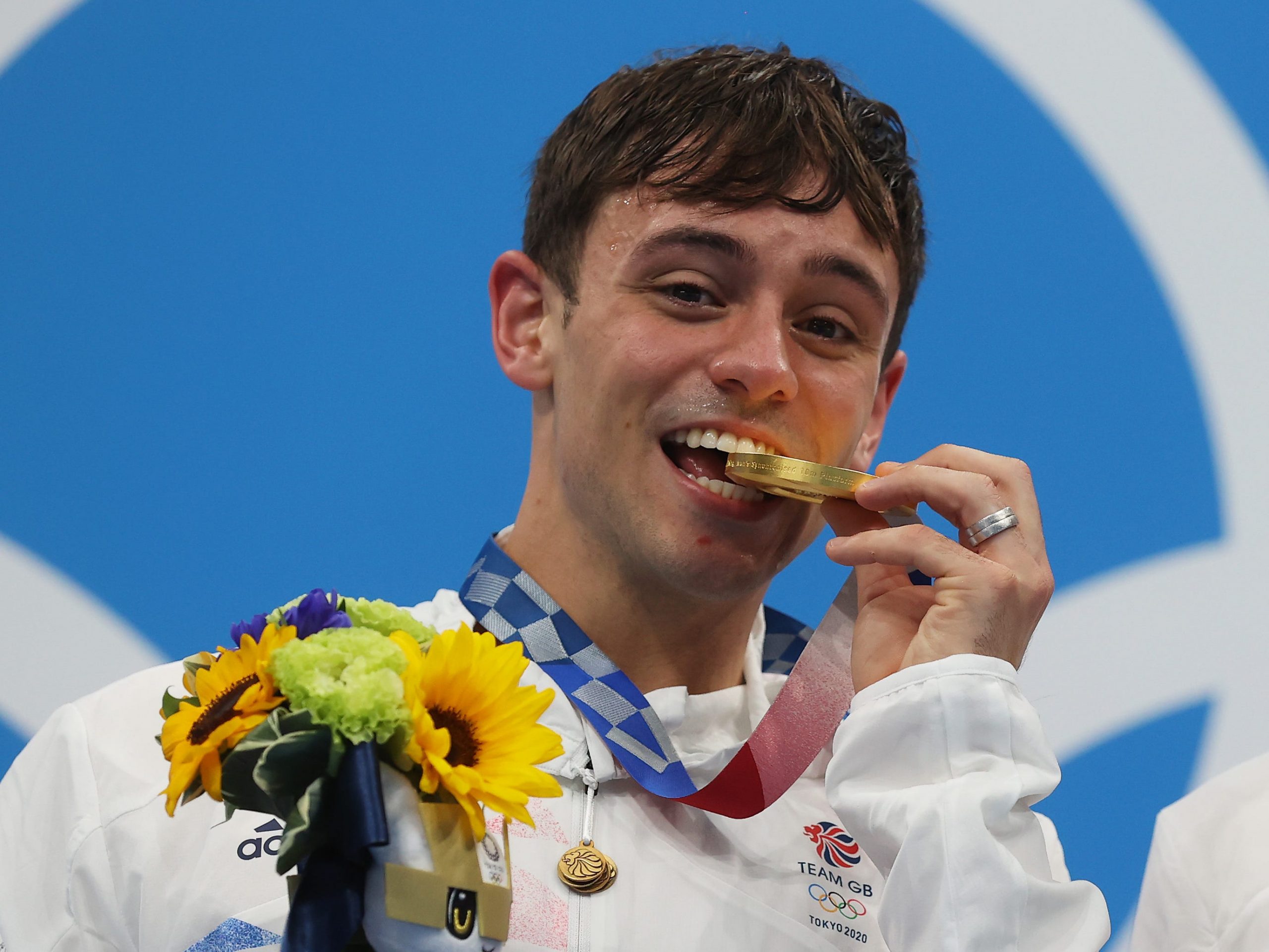 British diver Tom Daley biting his Tokyo Olympic gold medal