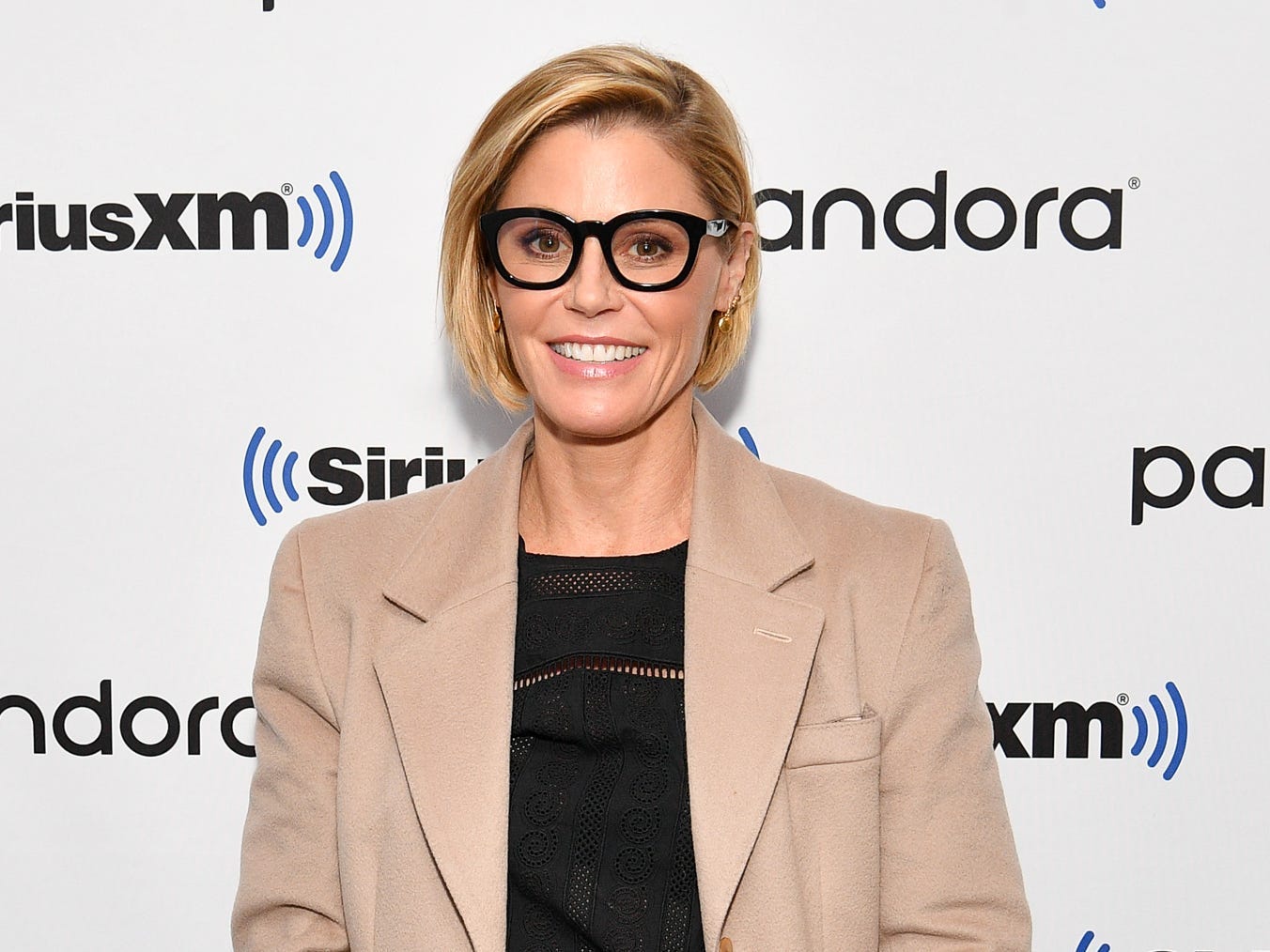 Julie Bowen poses for the cameras in a trench coat, black shirt, and jeans.