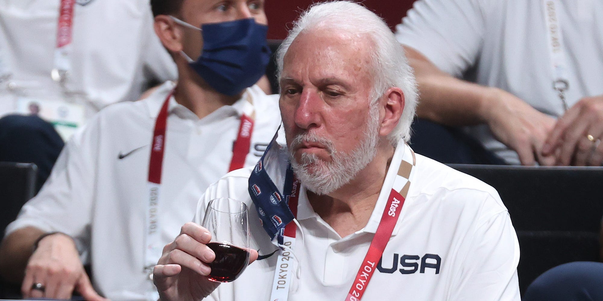 Gregg Popovich holds a wine glass at the Tokyo Olympics.