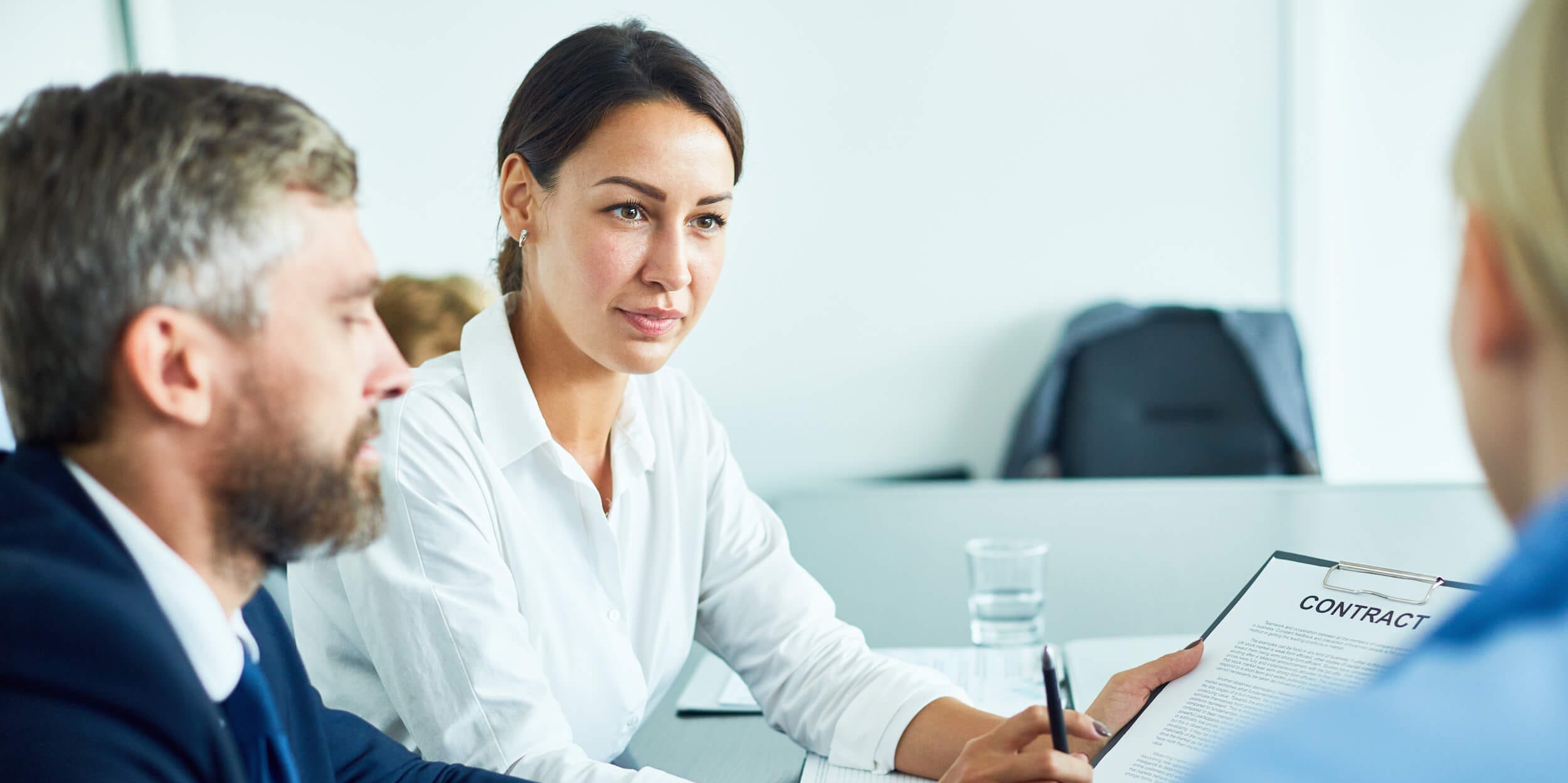 Business people in a meeting offering to sign a contract.