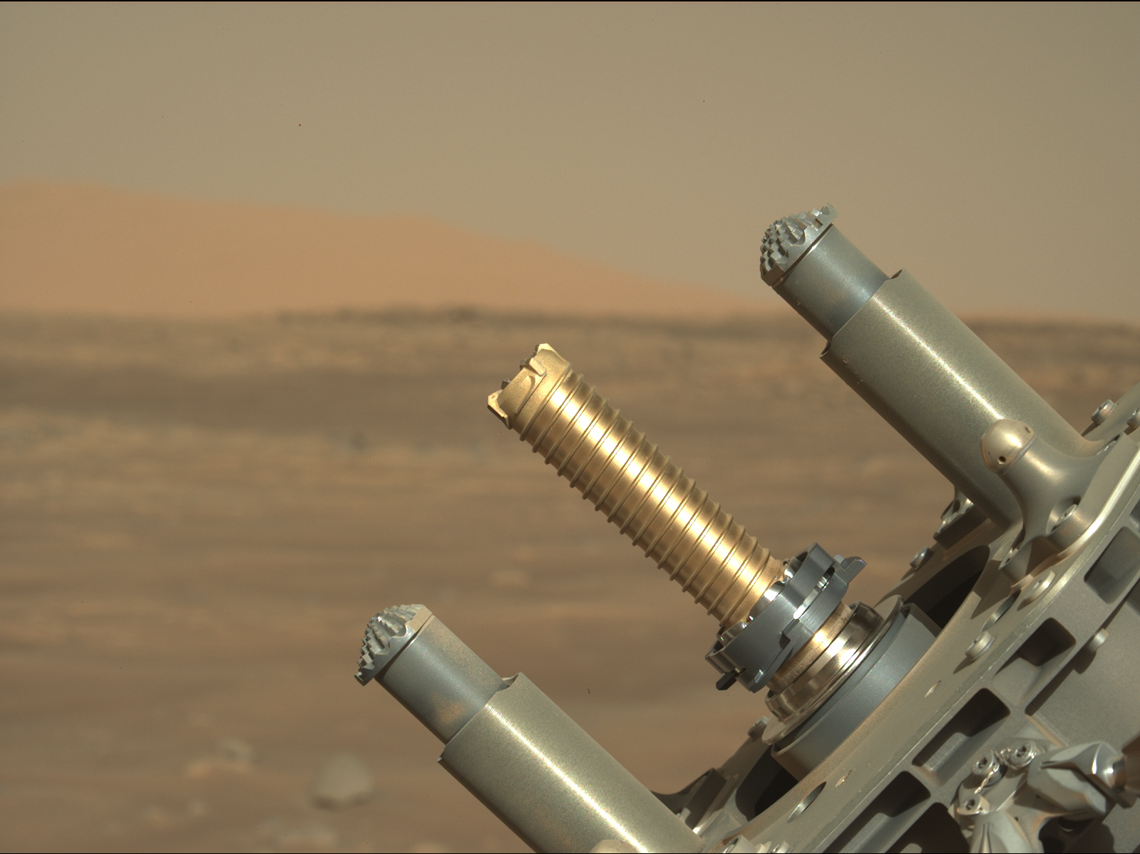 perseverance rover robotic arm holds up golden tube for coring samples against mars plains background