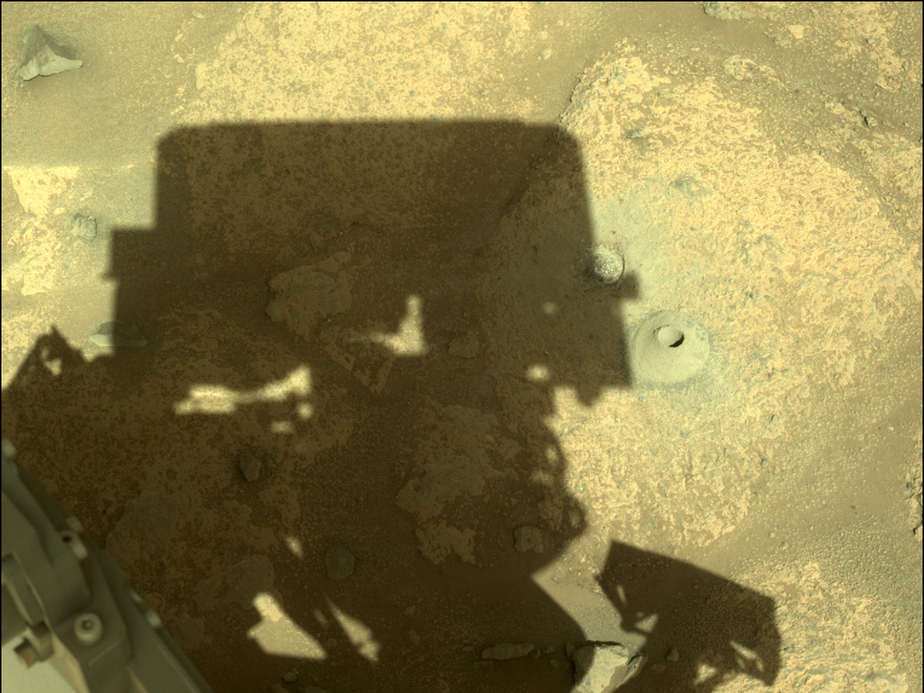 perseverance rover shadow looking down on hole in martian rock