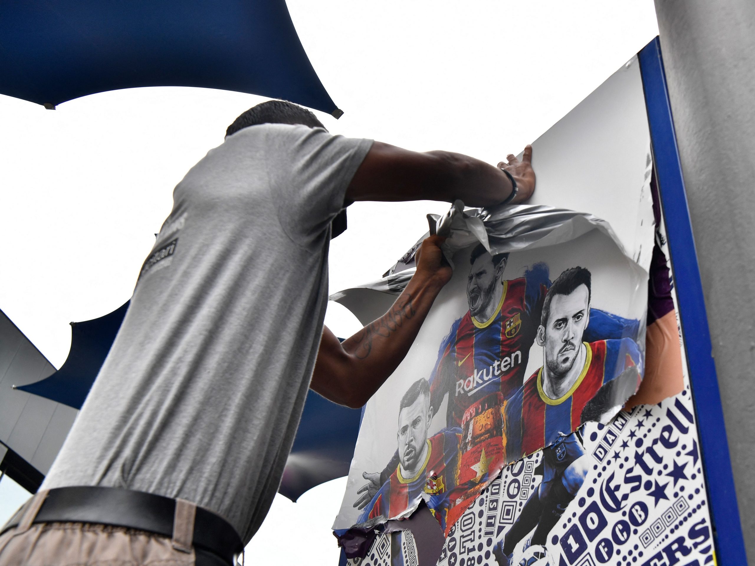 A worker removes posters featuring Barcelona's departing Argentinian forward Lionel Messi at the Camp Nou stadium in Barcelona