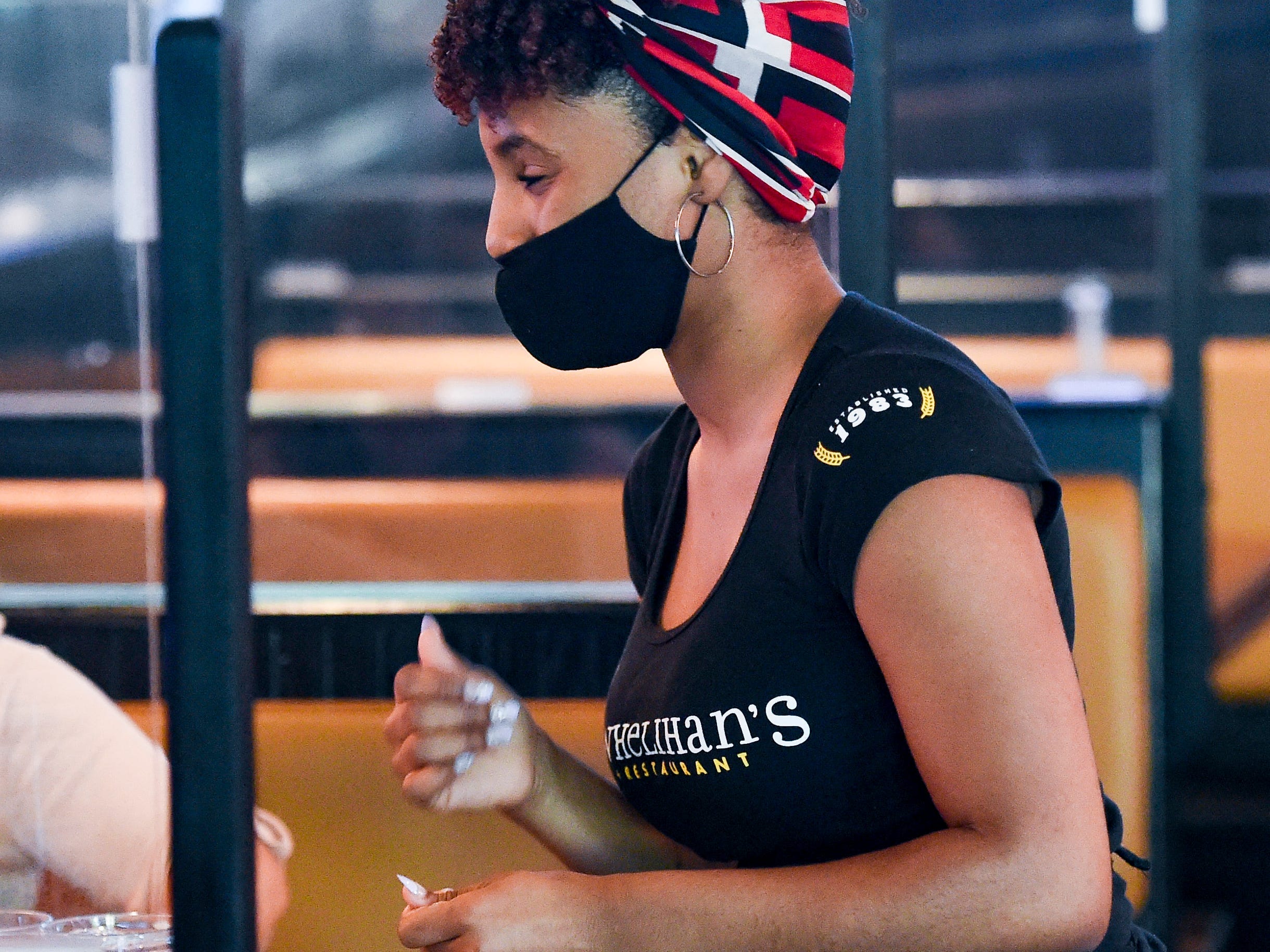 Server Gloria Gregorio talks to customers at a booth with plexiglass dividers. At P.J. Whelihan's restaurant and pub in Spring Township Friday evening June 25, 2021