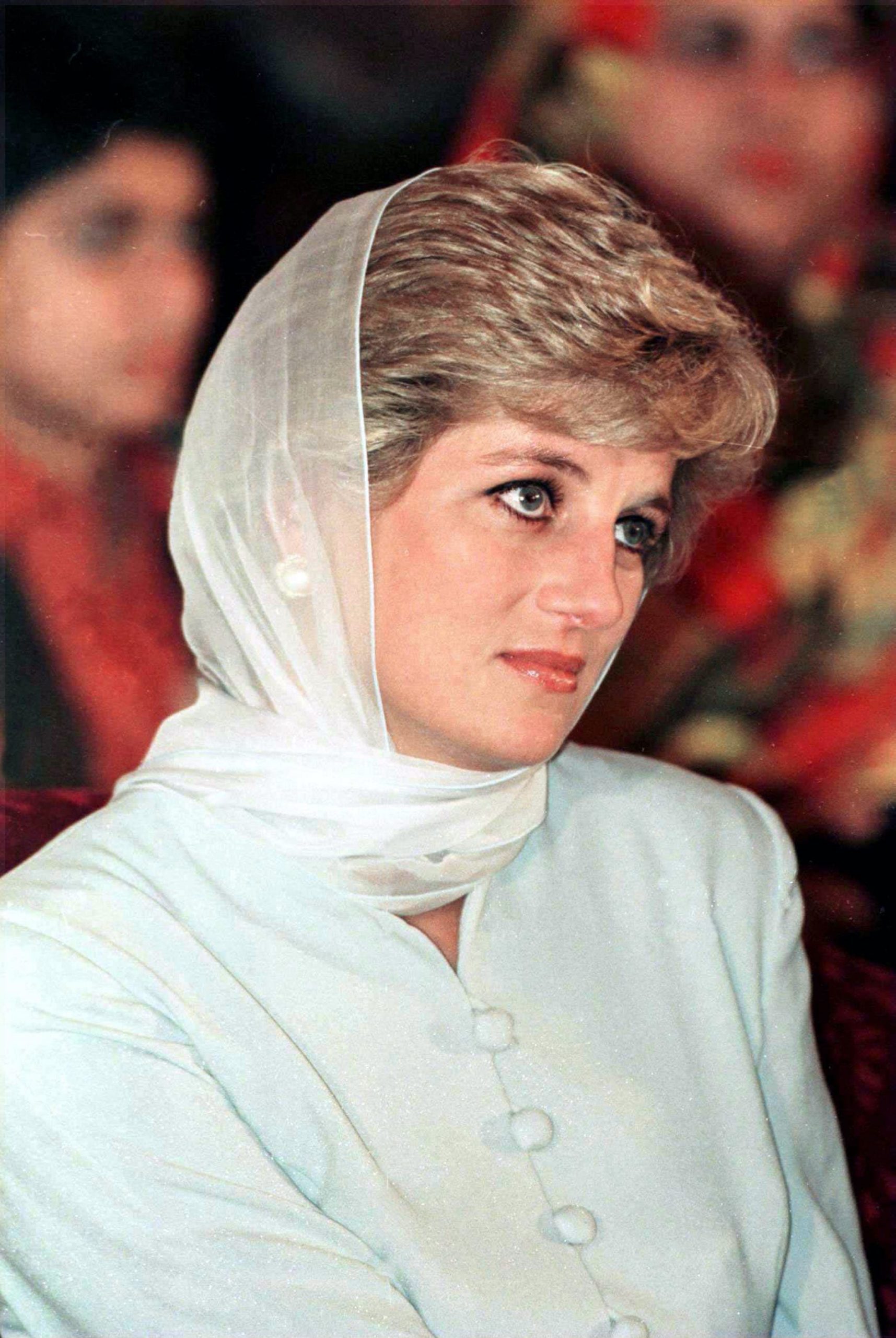 Princess Diana looks off to the right wearing a green blouse and matching head scarf.