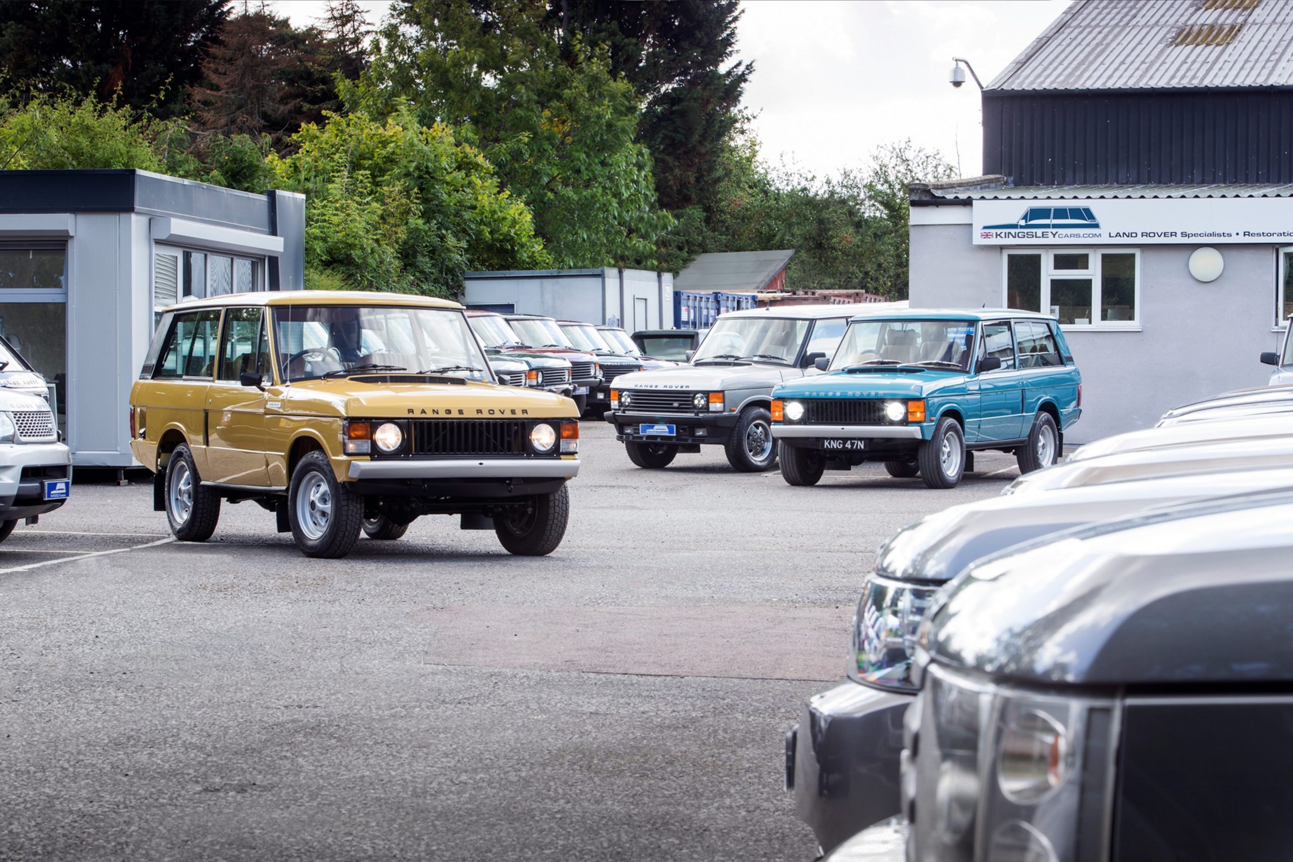 A group of Kingsley Cars Range Rovers in a shop parking lot.