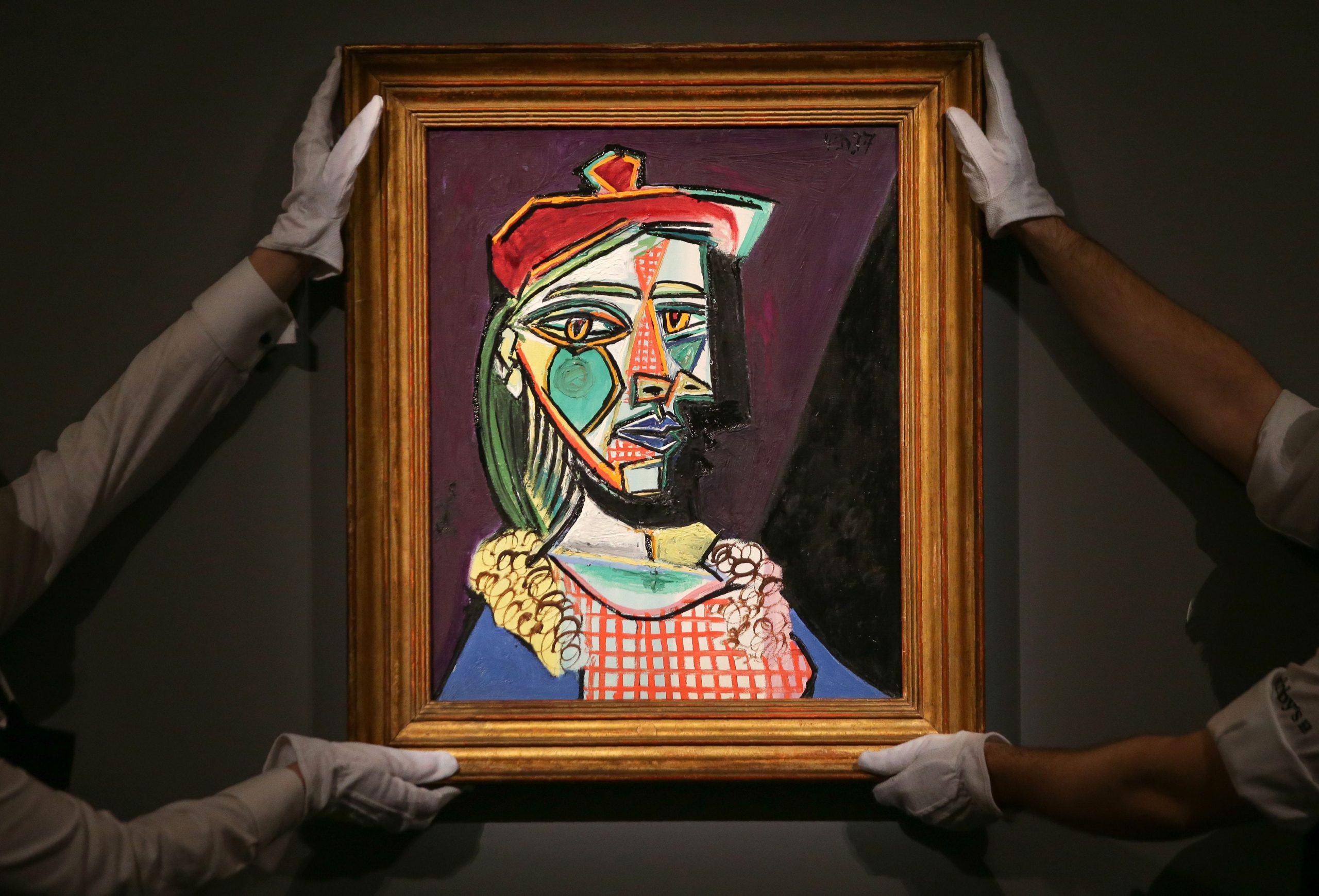 Gallery assistants hold an artwork by Spanish artist Pablo Picasso entitled 'Femme au beret et a la robe quadrillee' (Marie-Therese Walter) with an estimate price in the region of 35 million pounds, (50 million dollars), during a photocall at Sotheby's in central London on February 22, 2018
