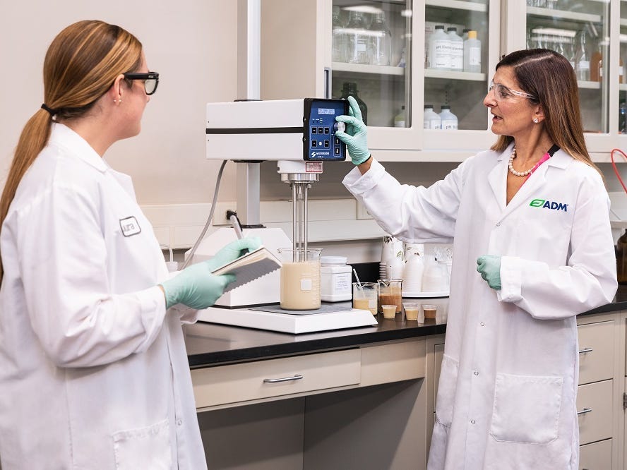 two women in lab coats testing flavors in a lab