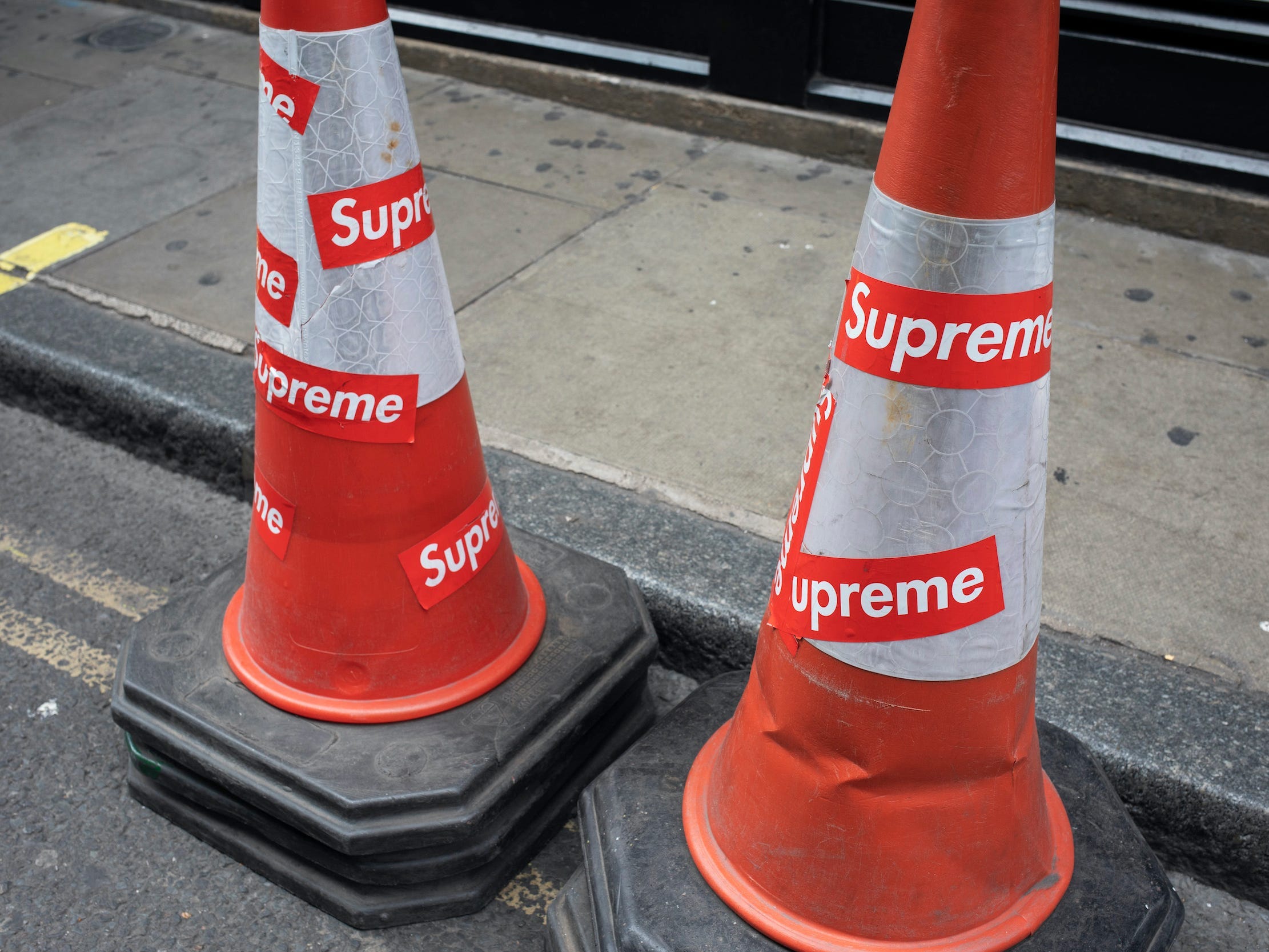 Cones with Supreme stickers sit on a street outside Supreme store in London