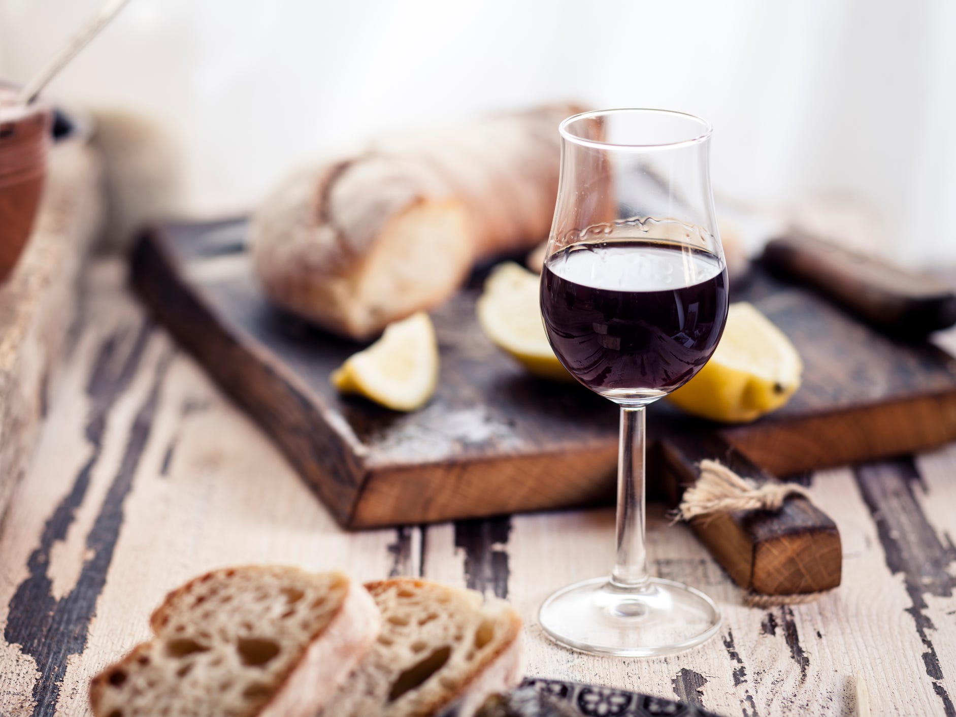 A glass of wine in front of a plate of bread.