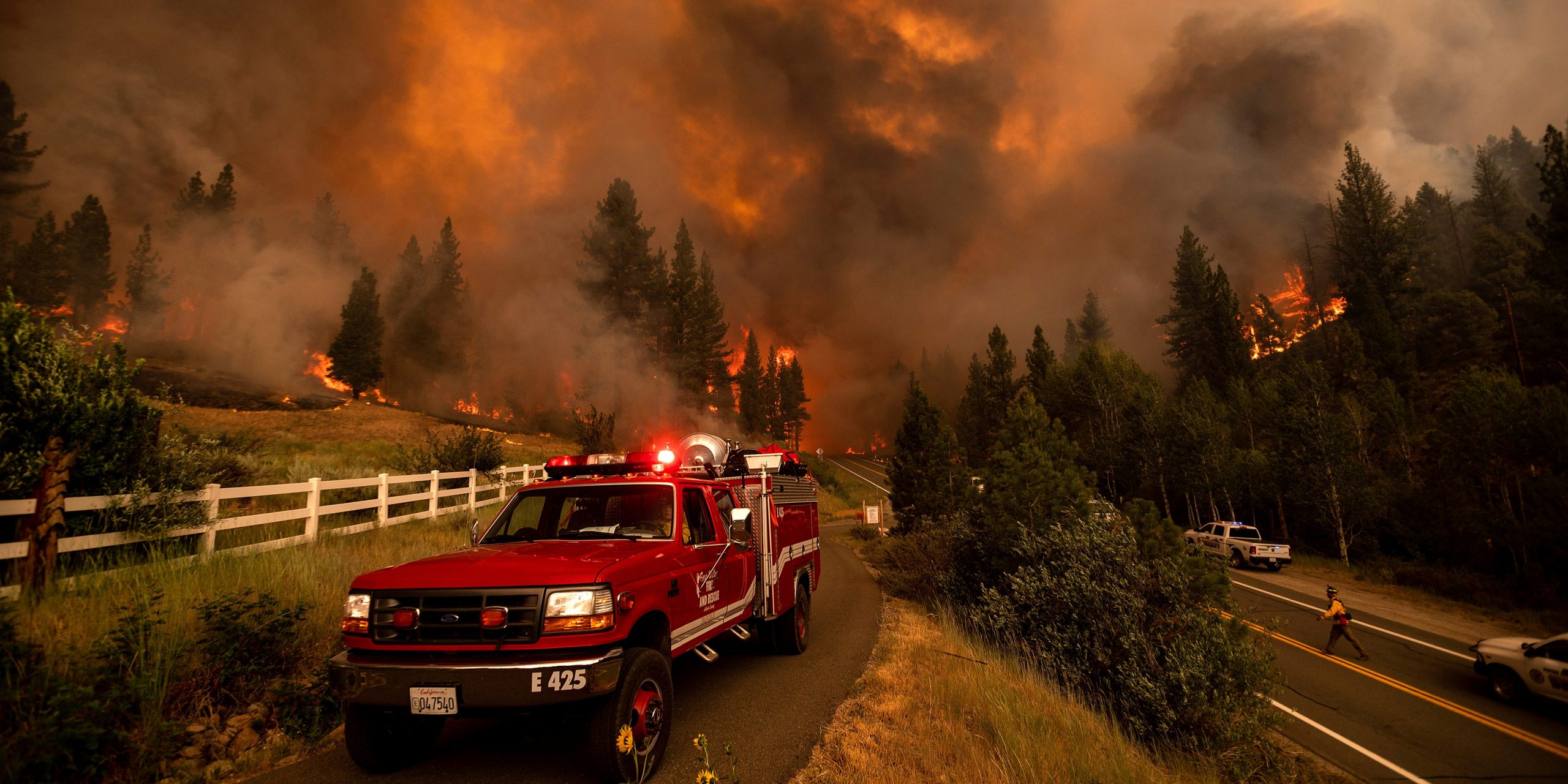 A fire truck in front of a blazing fire.