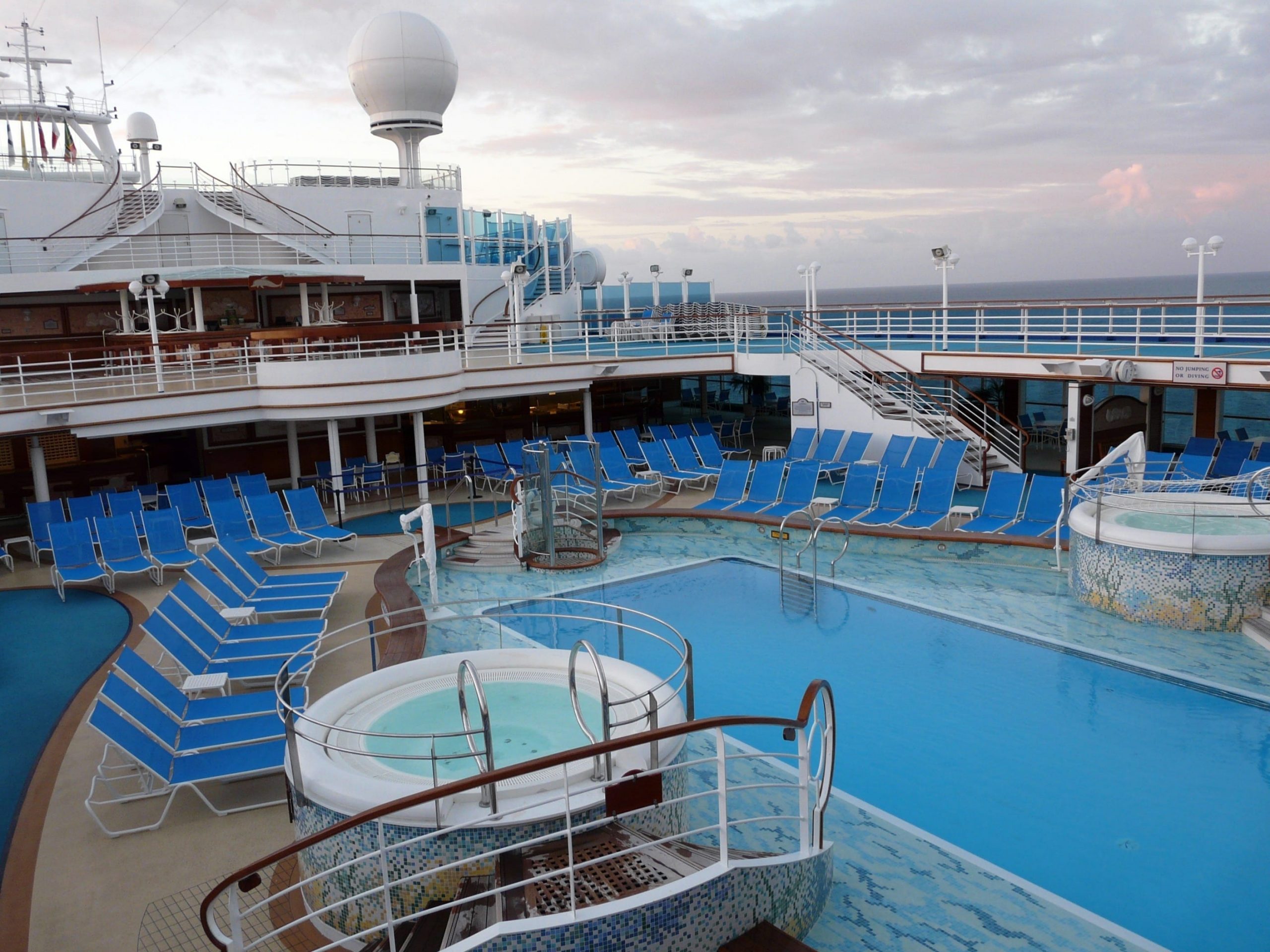 Cruise ship deck with blue chairs and long pool