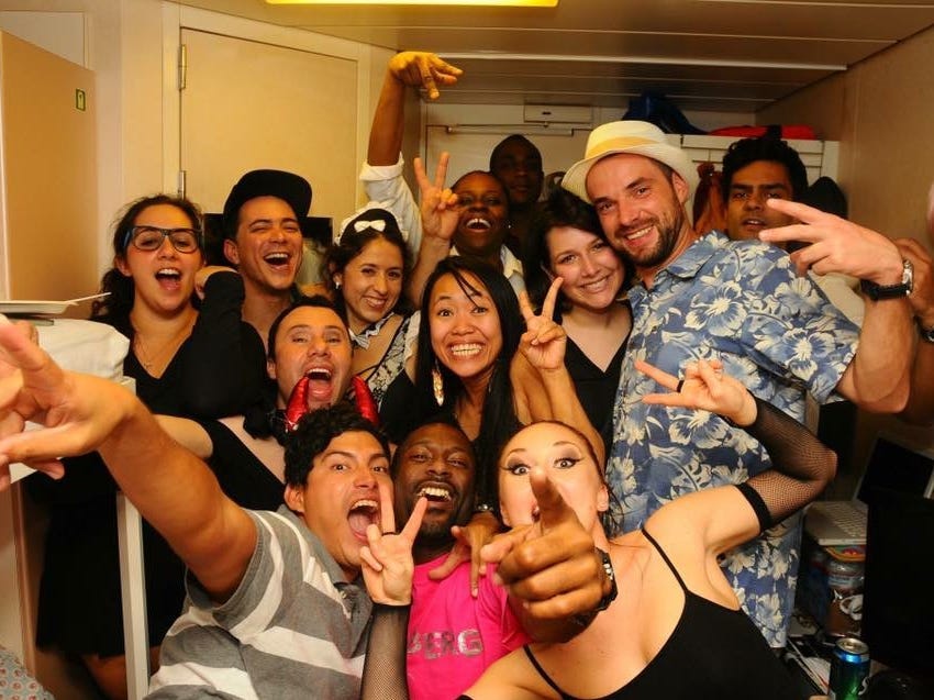 Cruise ship employees posing for a photo in a room