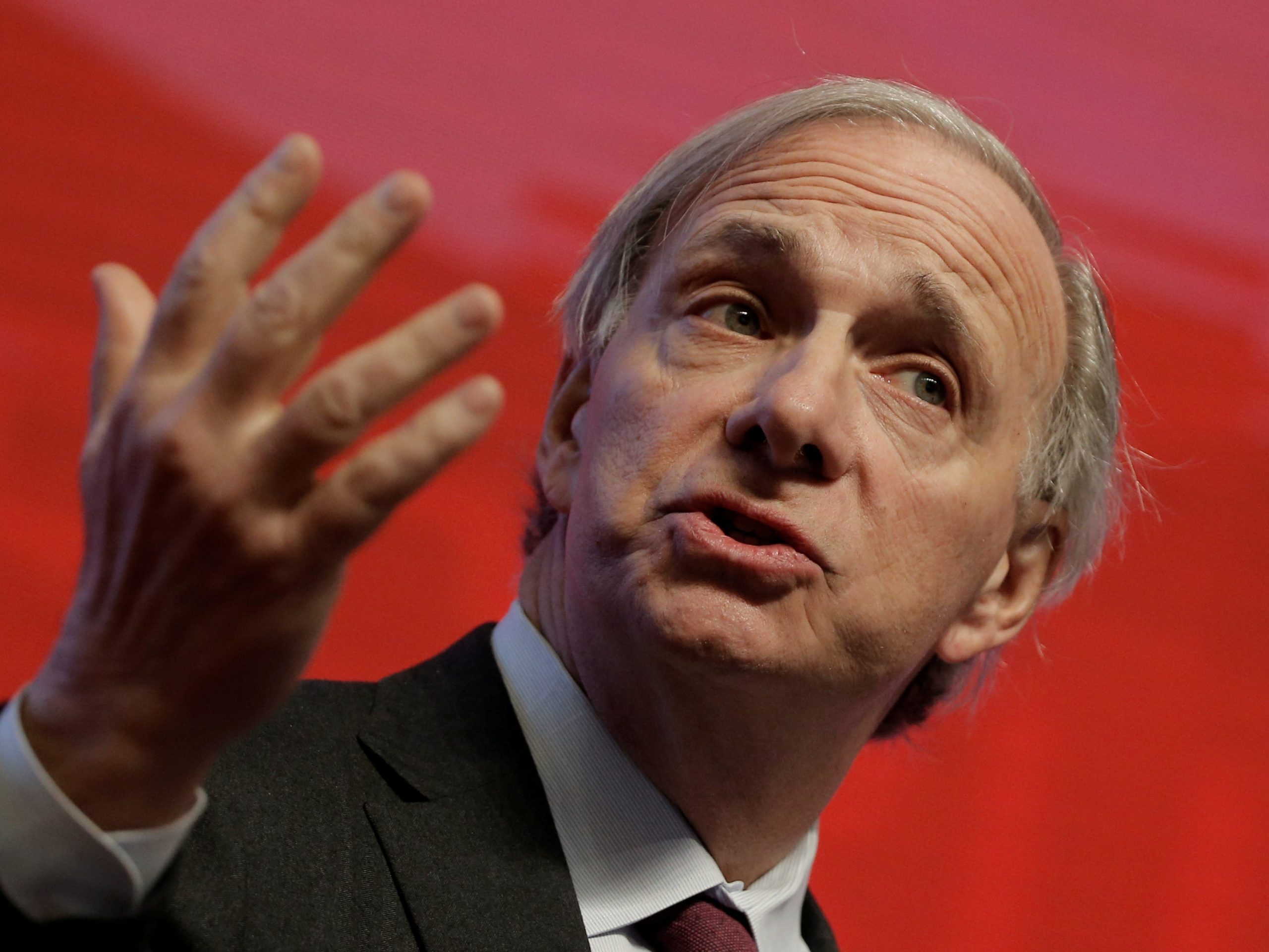 Ray Dalio stands against a red background.