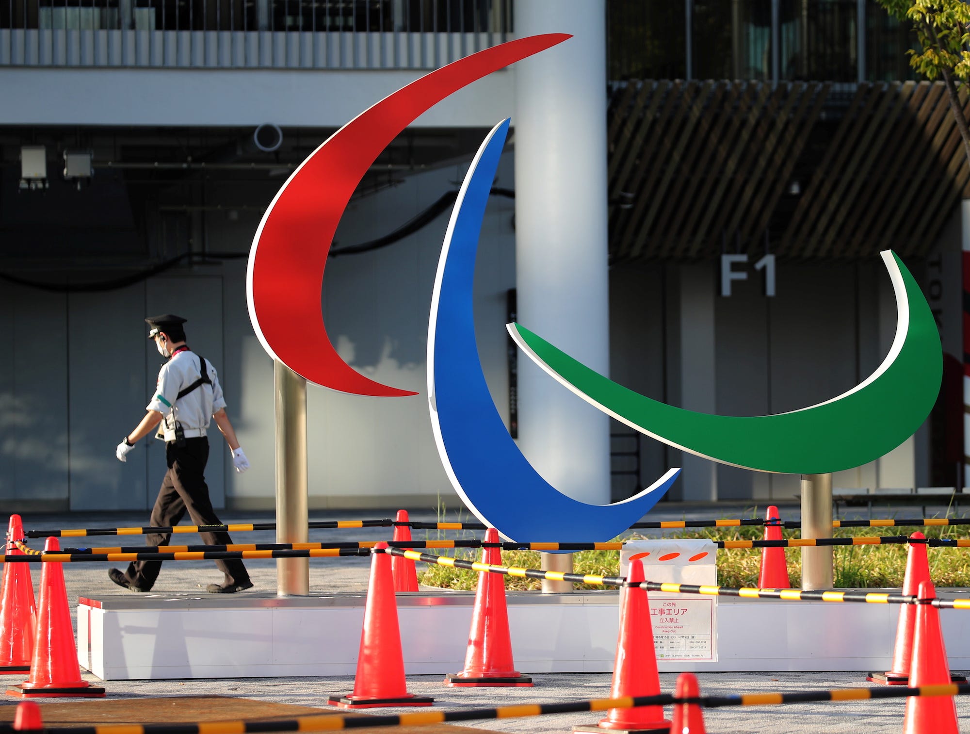 A security guard wearing a protective mask, amid the coronavirus disease (COVID-19) outbreak, walks past the symbol of the Paralympic Games under installation at the National Stadium, the main venue of the Tokyo 2020 Olympic and Paralympic Games