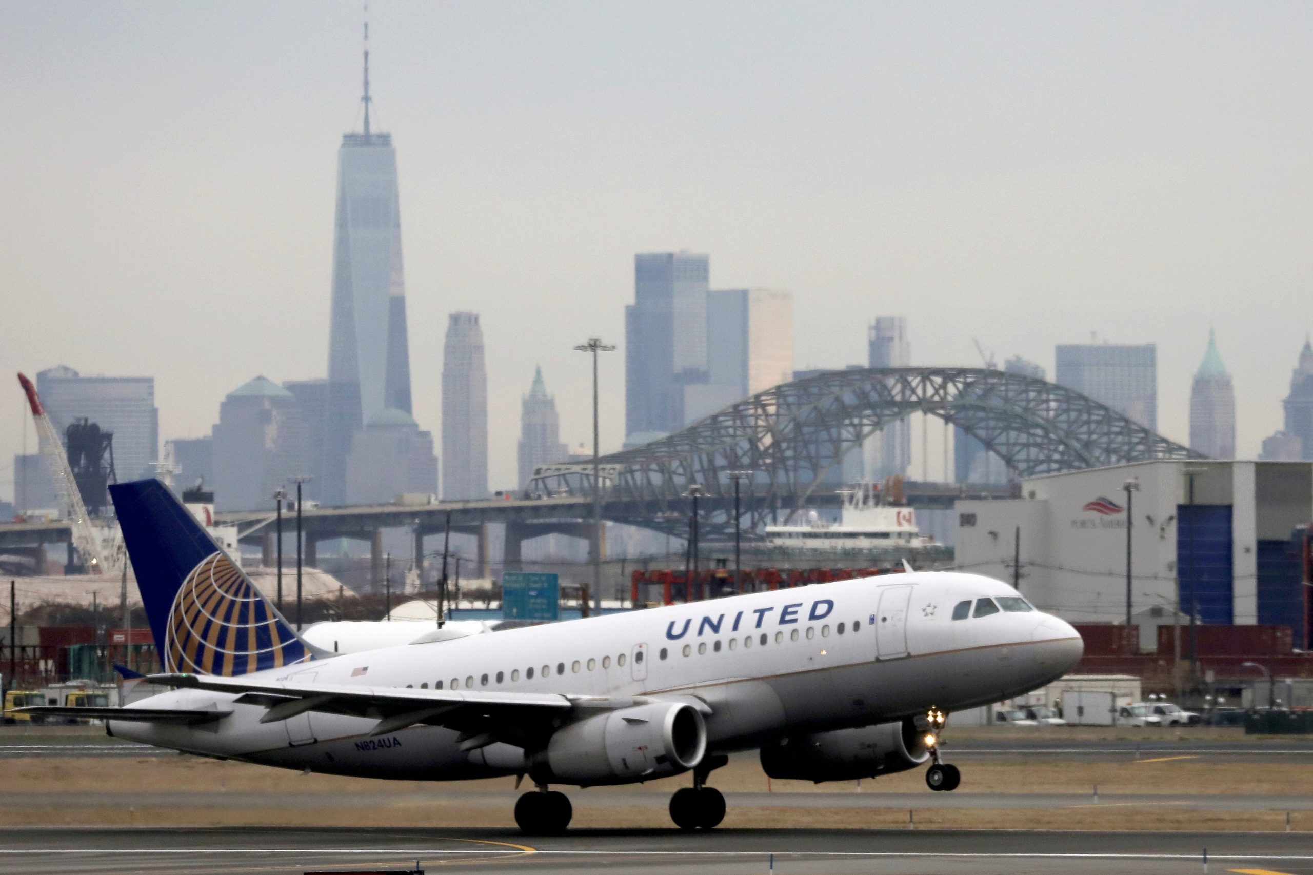 A white United Airlines plane sits on a runway in front of the New York City skyline.