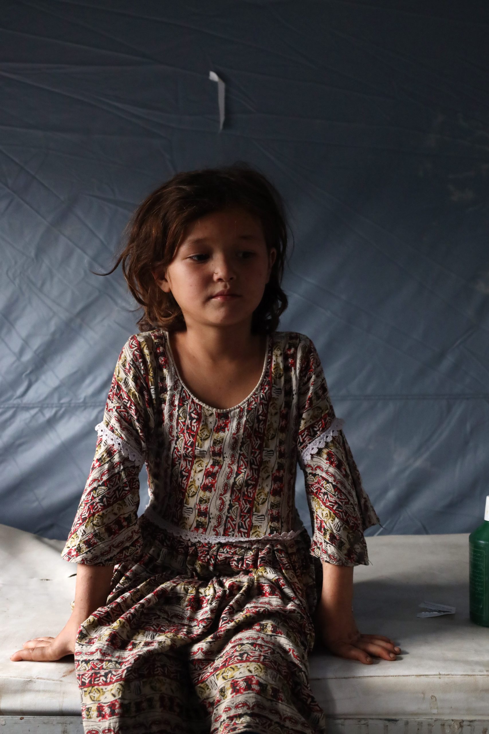 a little girl sits on a table in a tent in kabul