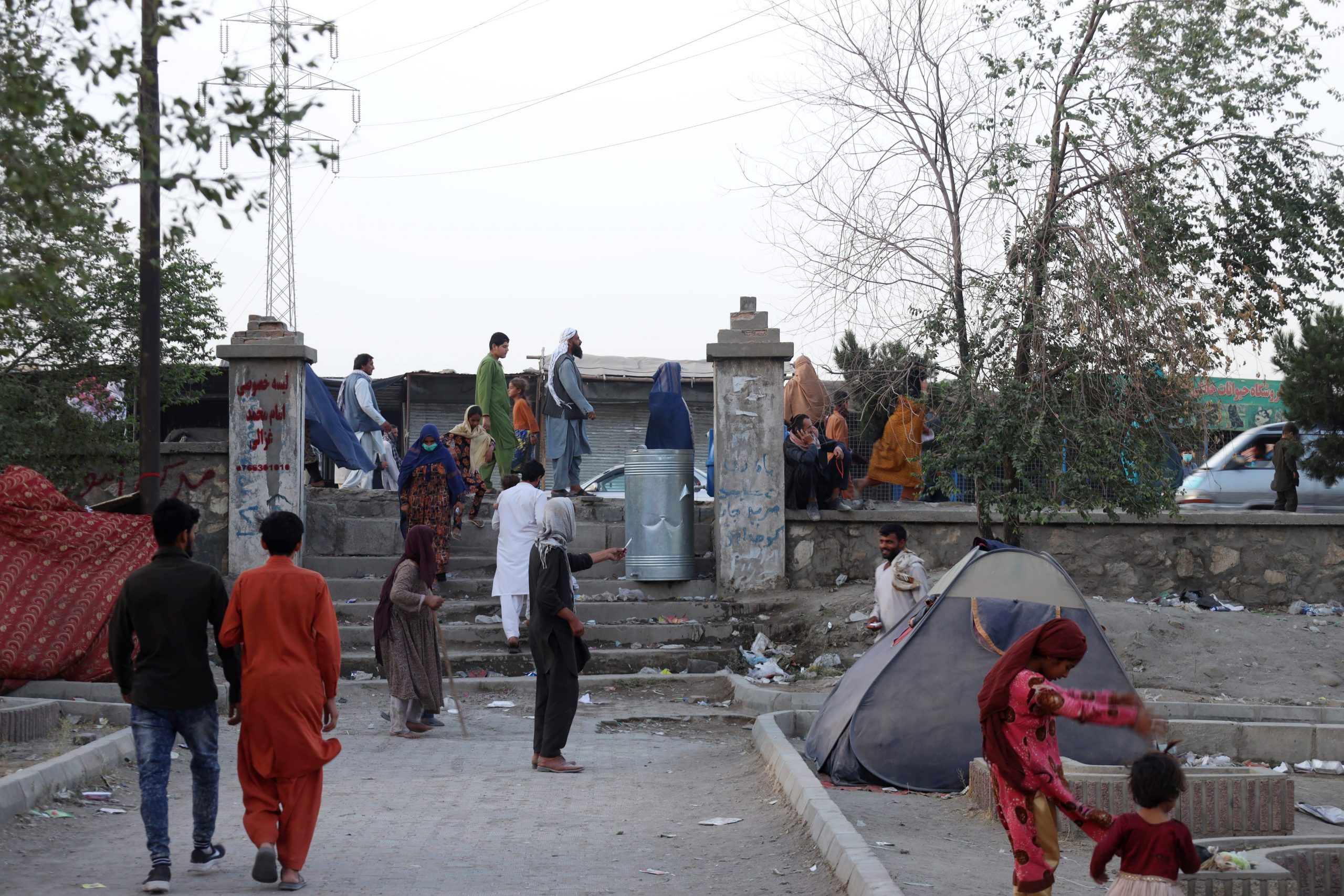people mill about a makeshift refugee camp in kabul