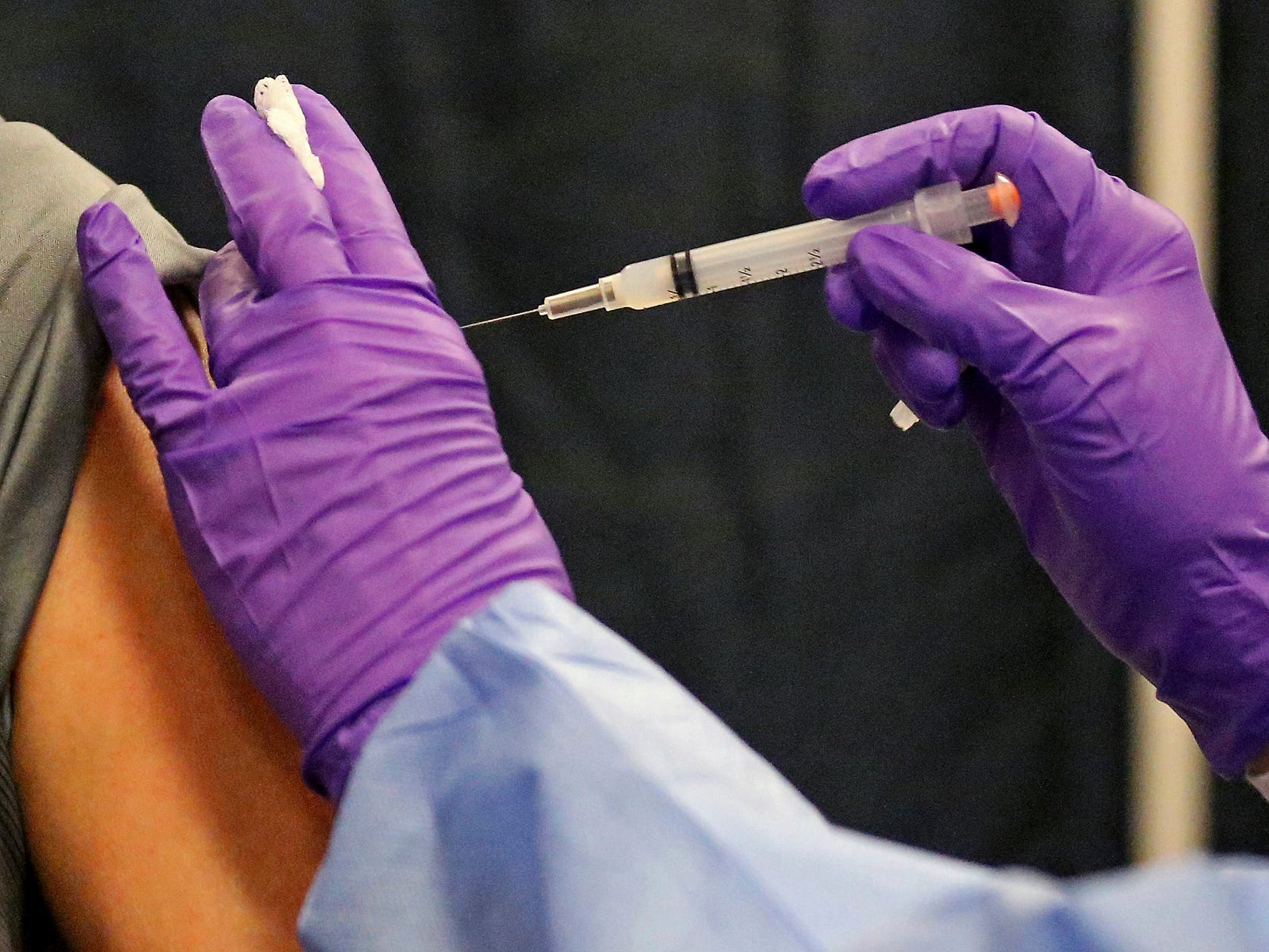 A man gets a COVID-19 vaccine at a mass vaccination site at the Natick Mall on Wednesday, Feb. 24, 2021, in Natick, Mass.