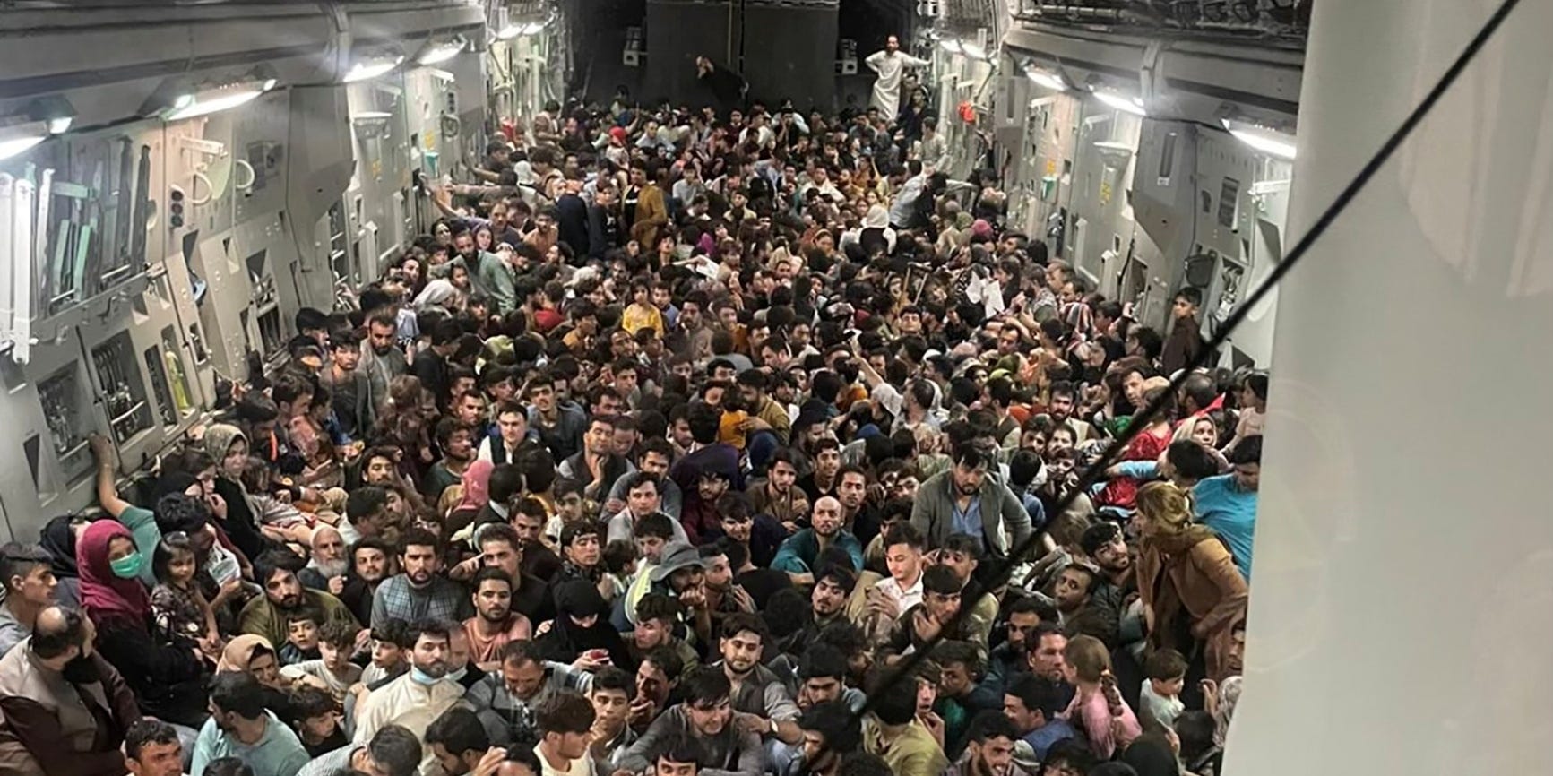 Hundreds of people sitting on the floor of a transport aircraft